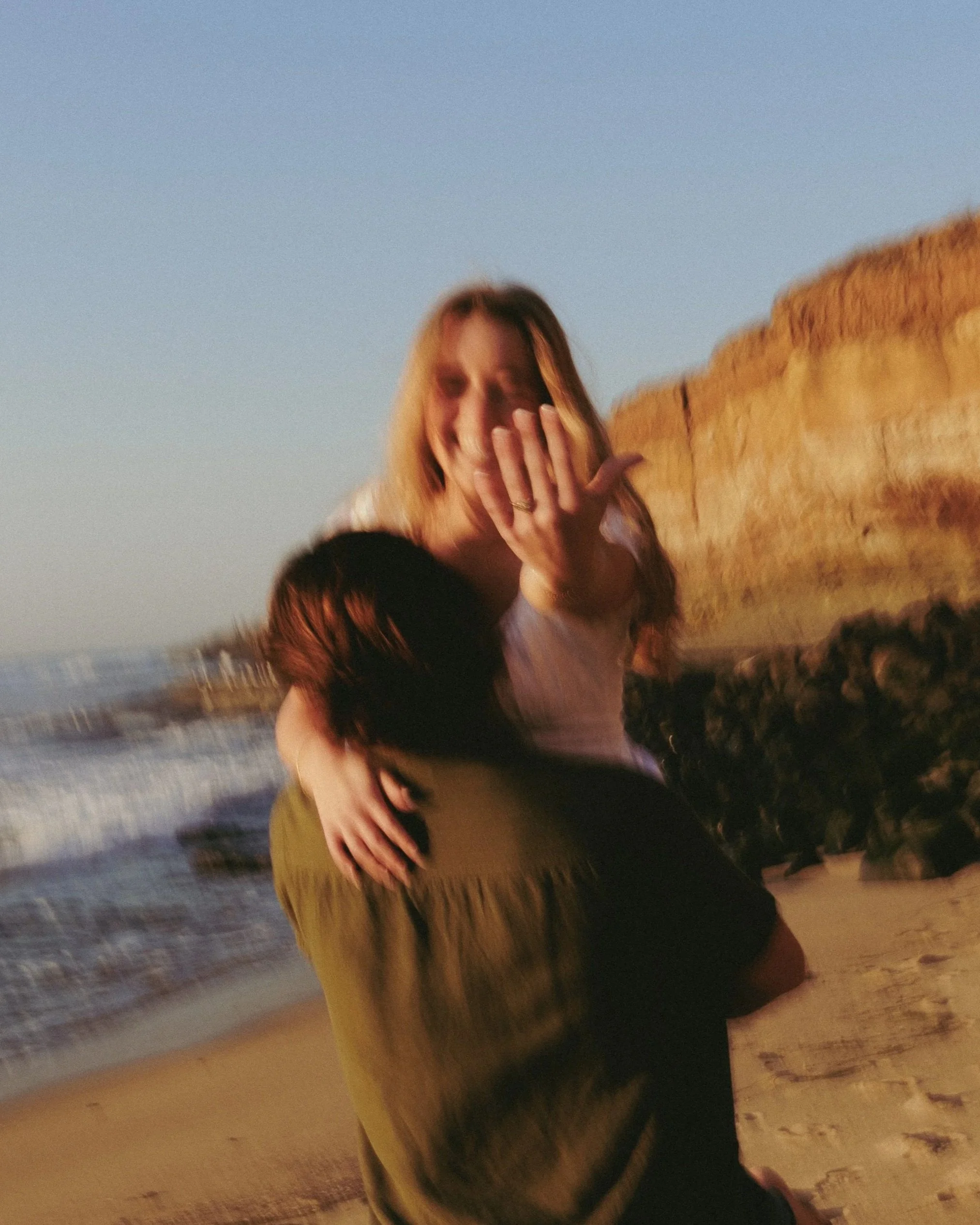 Professional proposal photograph of a happy woman being carried by her fiance after saying yes