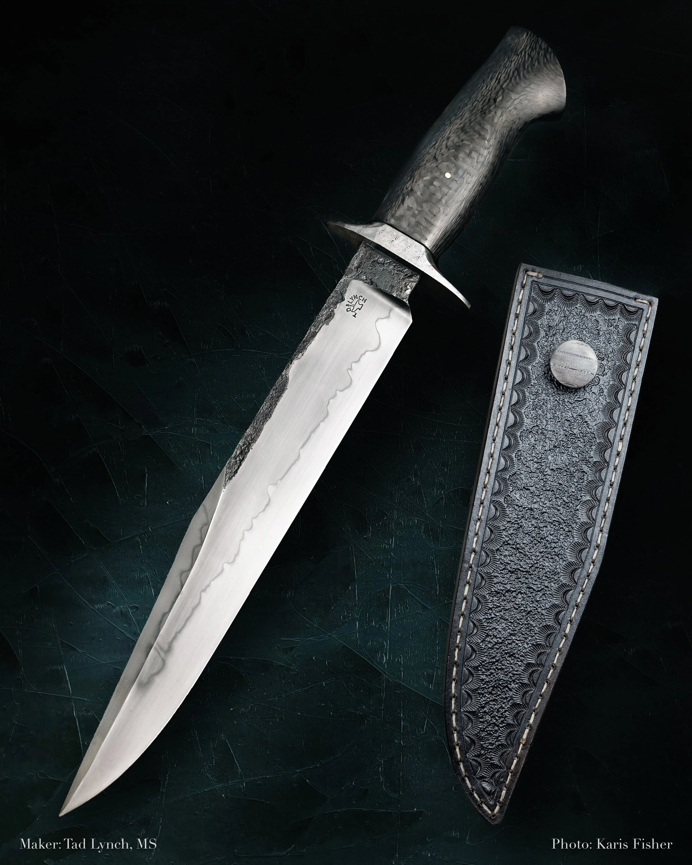 A knife with a hammered metal handle and a wavy-edged blade, resting next to a decorative leather sheath with a button closure.