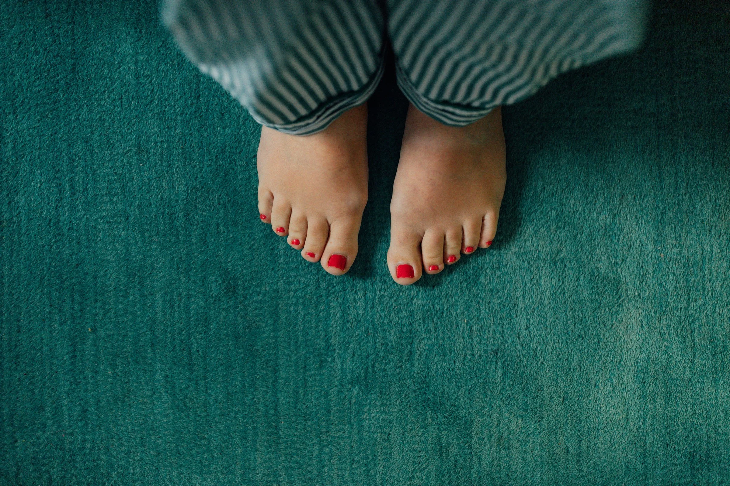 A view looking down at a pair of bare feet and striped pajama pants.