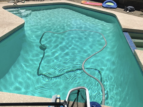Swimming pool with pool vacuum hose floating on water