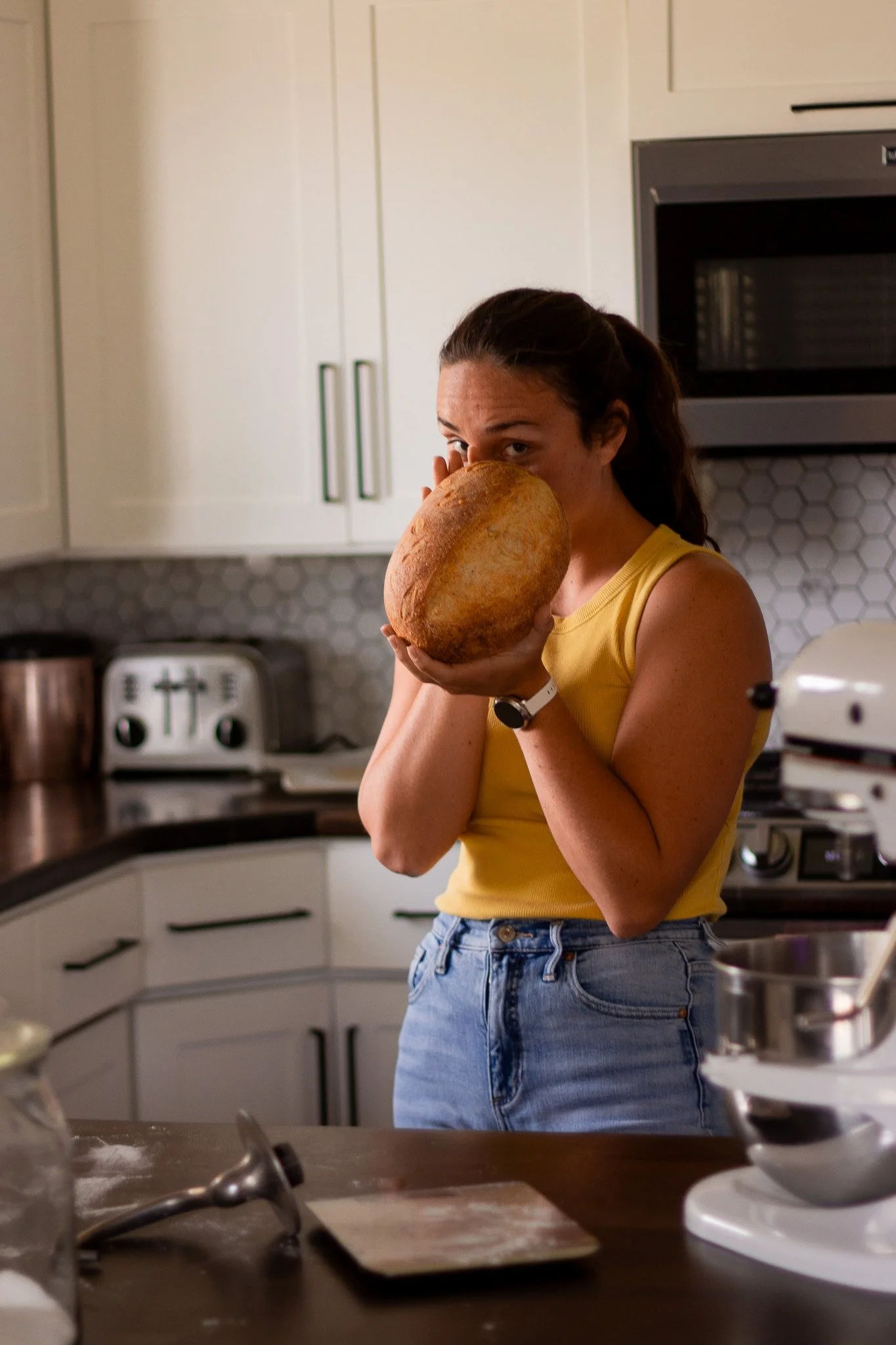 Aleisha holding a Sourdough loaf in the kitchen