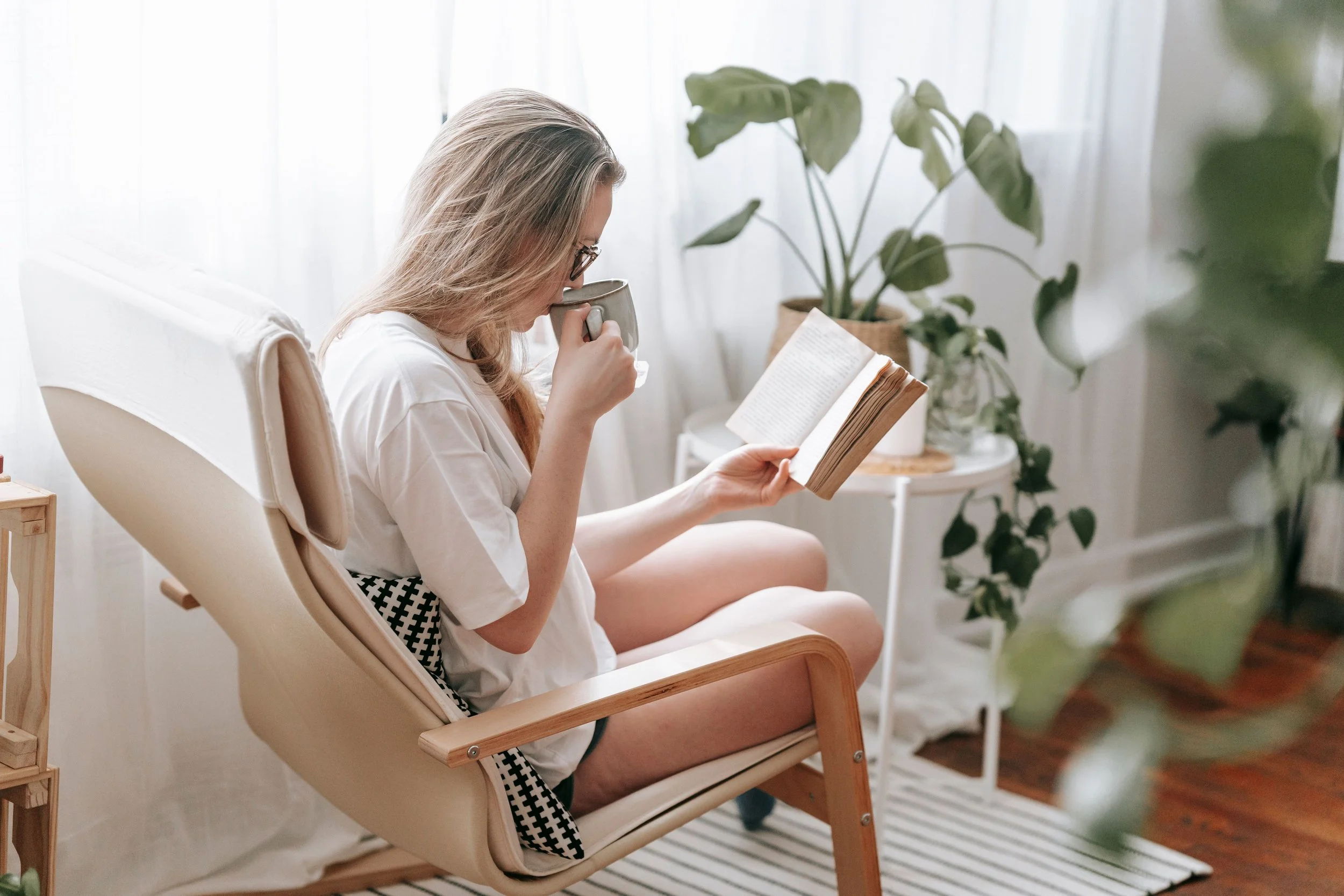 An adult relaxing with a warm cup of tea in a sunlit room, illustrating nervous system regulation and the relief that comes from therapy for stress and burnout.