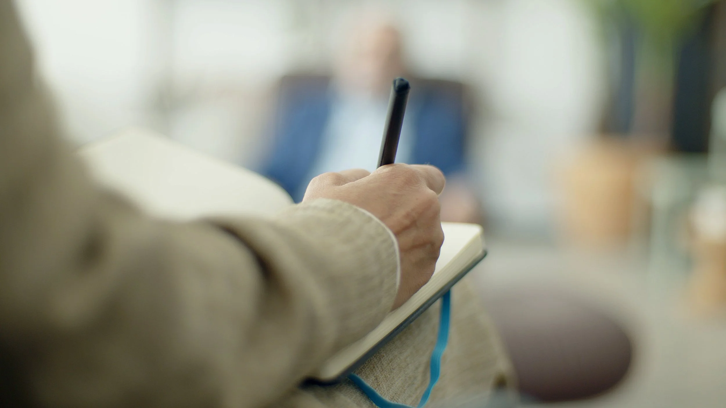 A close-up of a person journaling with a warm cup of tea, representing the new layers of awareness and deep healing that emerge after a trauma therapy intensive.
