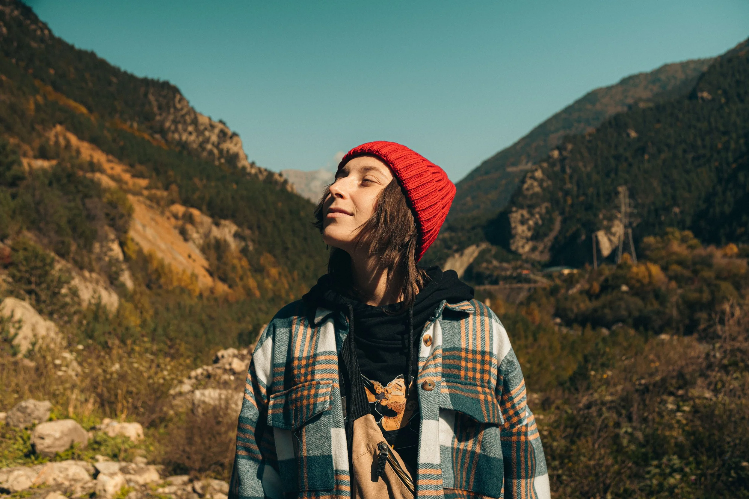 An adult taking a deep, grounding breath while walking outdoors, representing nervous system regulation and the integration phase after a therapy intensive.
