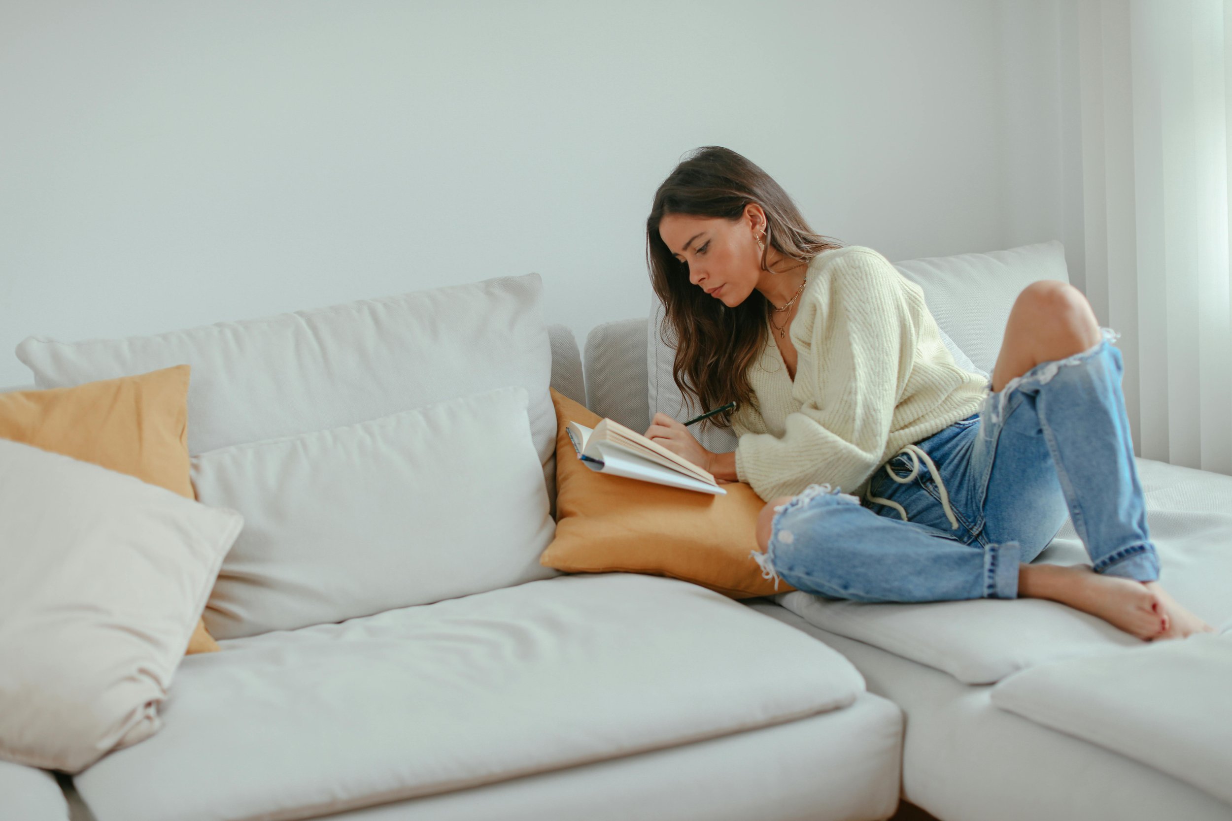 An adult writing in a journal on a sofa, taking time to integrate the deep emotional shifts experienced after an EMDR therapy intensive in Illinois.