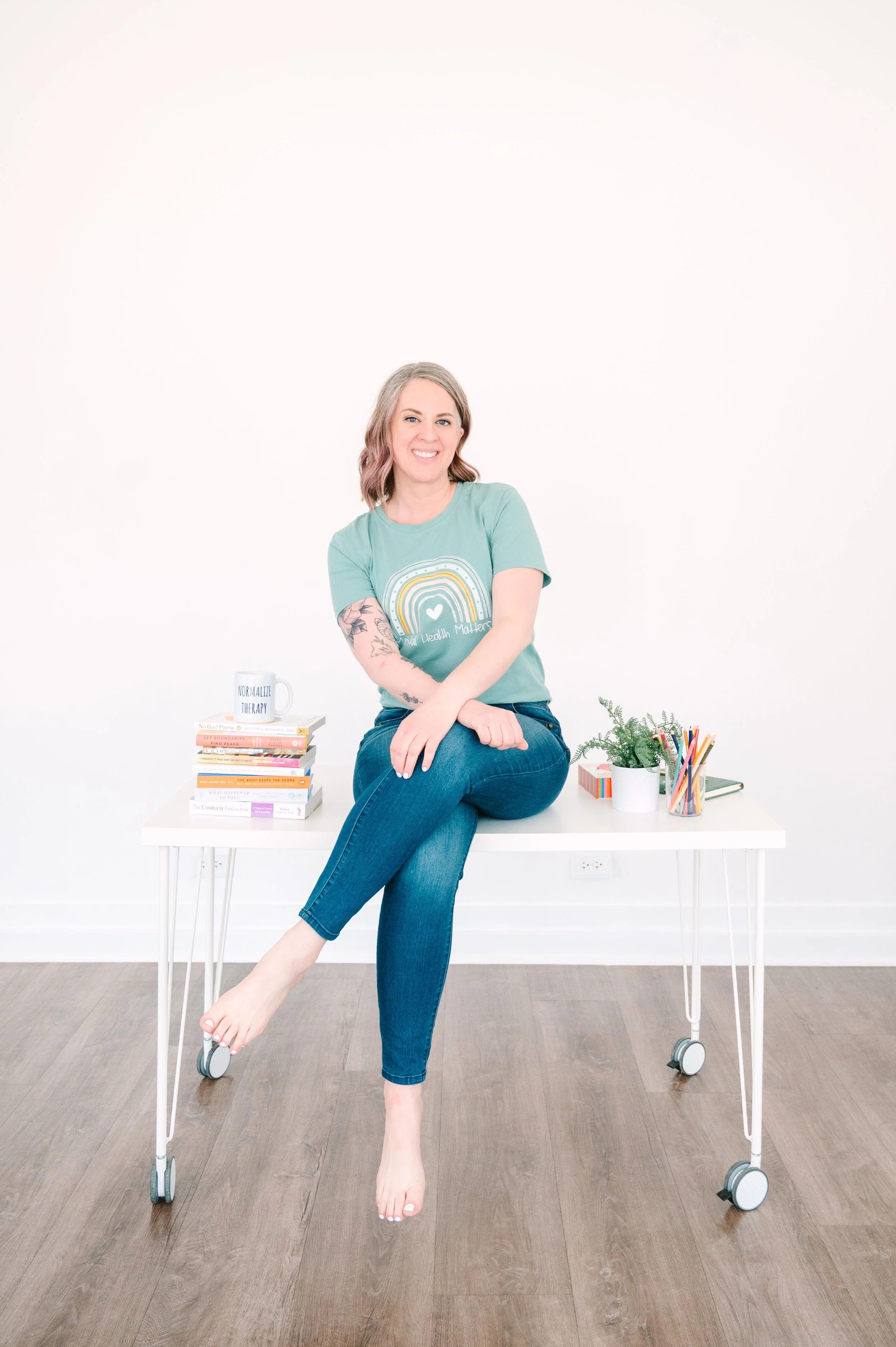 Trauma therapist sitting on desk in Holly Springs NC office offering EMDR and therapy intensives for anxiety and trauma.