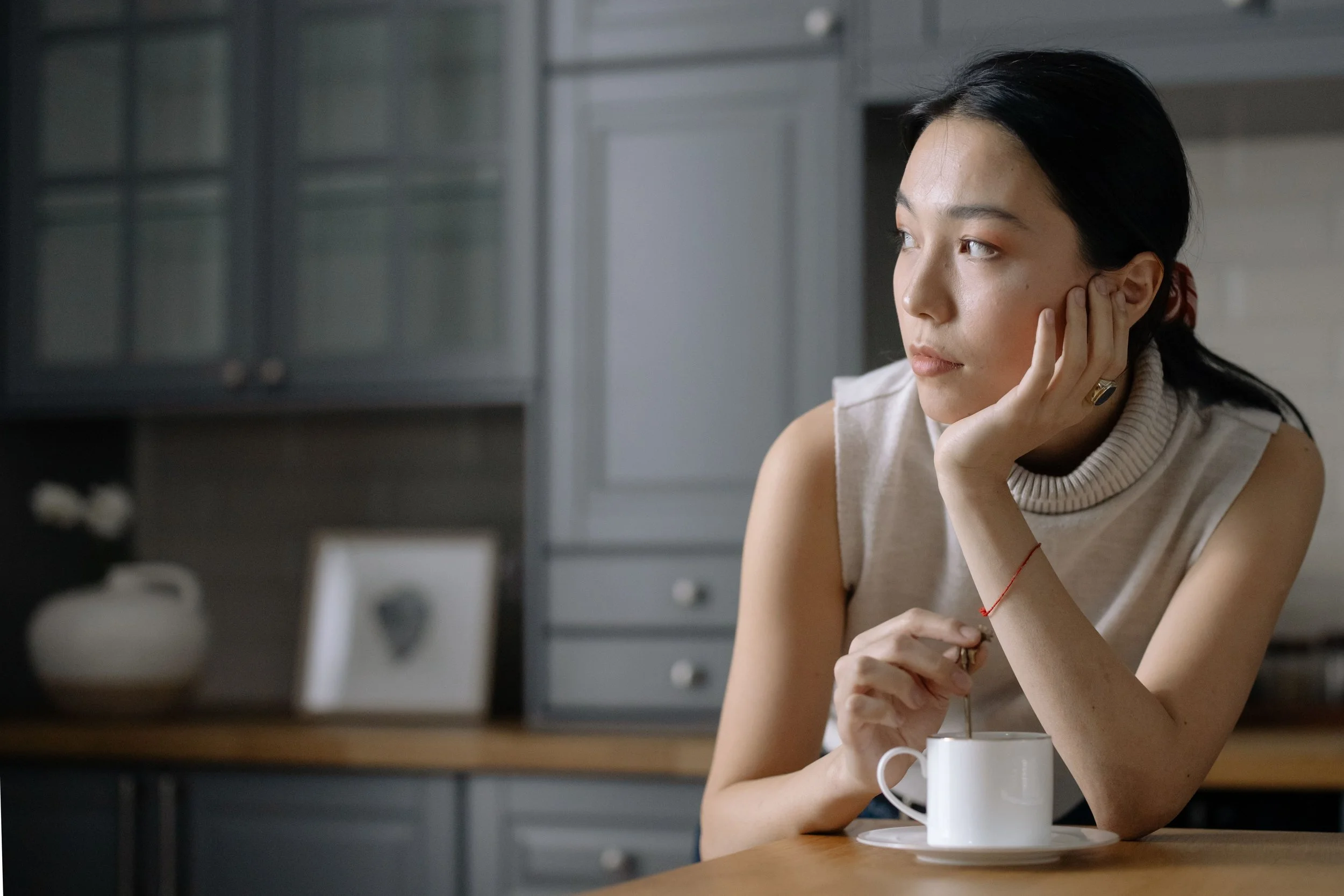 A thoughtful adult holding a warm mug, contemplating if a therapy intensive will be too emotionally intense and considering their healing journey.