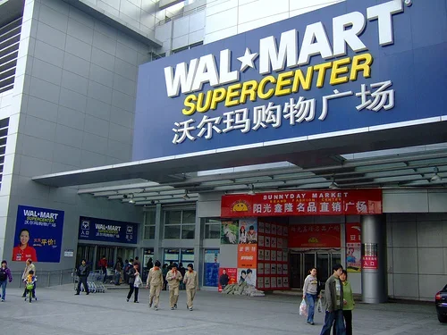 People entering and exiting a Walmart Supercenter store with signage in English and Chinese.