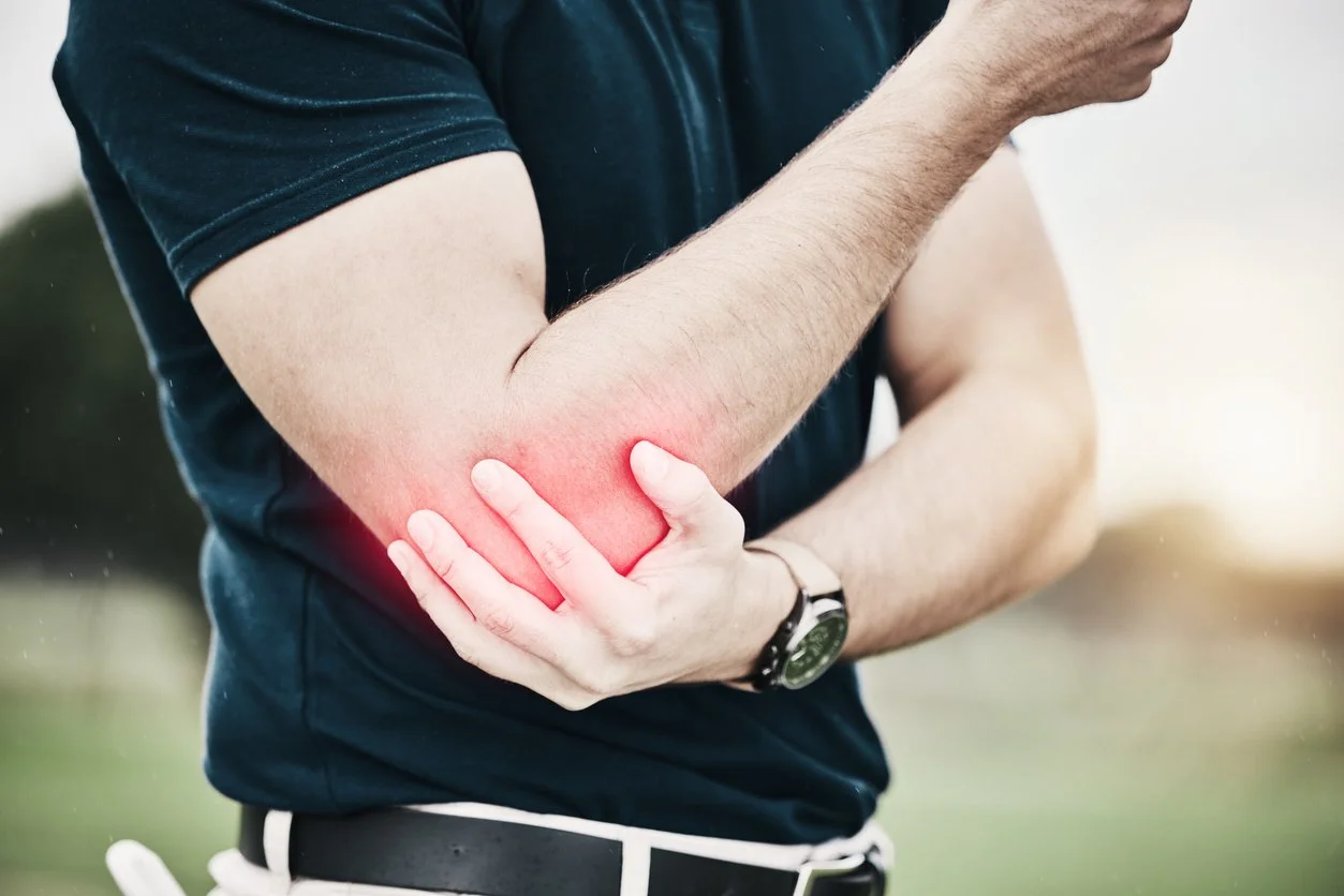 A person holding their elbow, which is red and appears to be sore or inflamed.