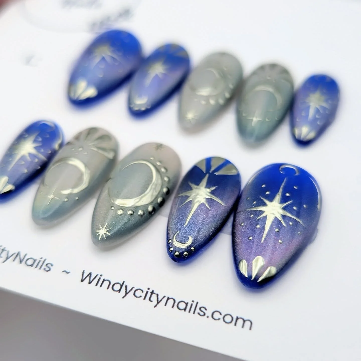 This design is named Celestial Reverie and is for sale now on windycitynails.com! 

This set gives a night sky at your fingertips. The rich blue and holographic rainbow shifts with chrome moons and stars add to the celestial vibes. 🌕✨

Are you ready