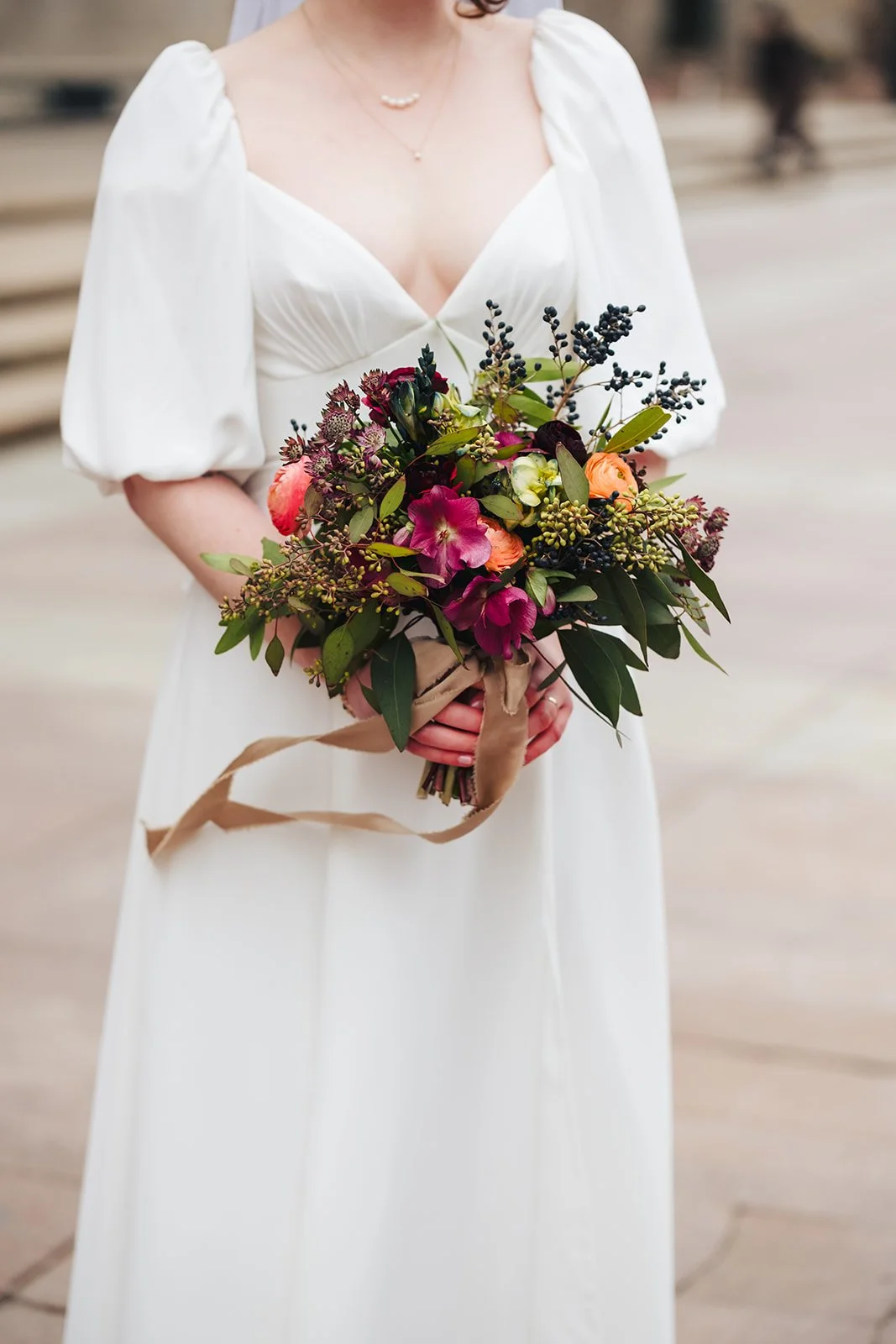 A woman in a white dress holding a colorful bouquet of flowers.