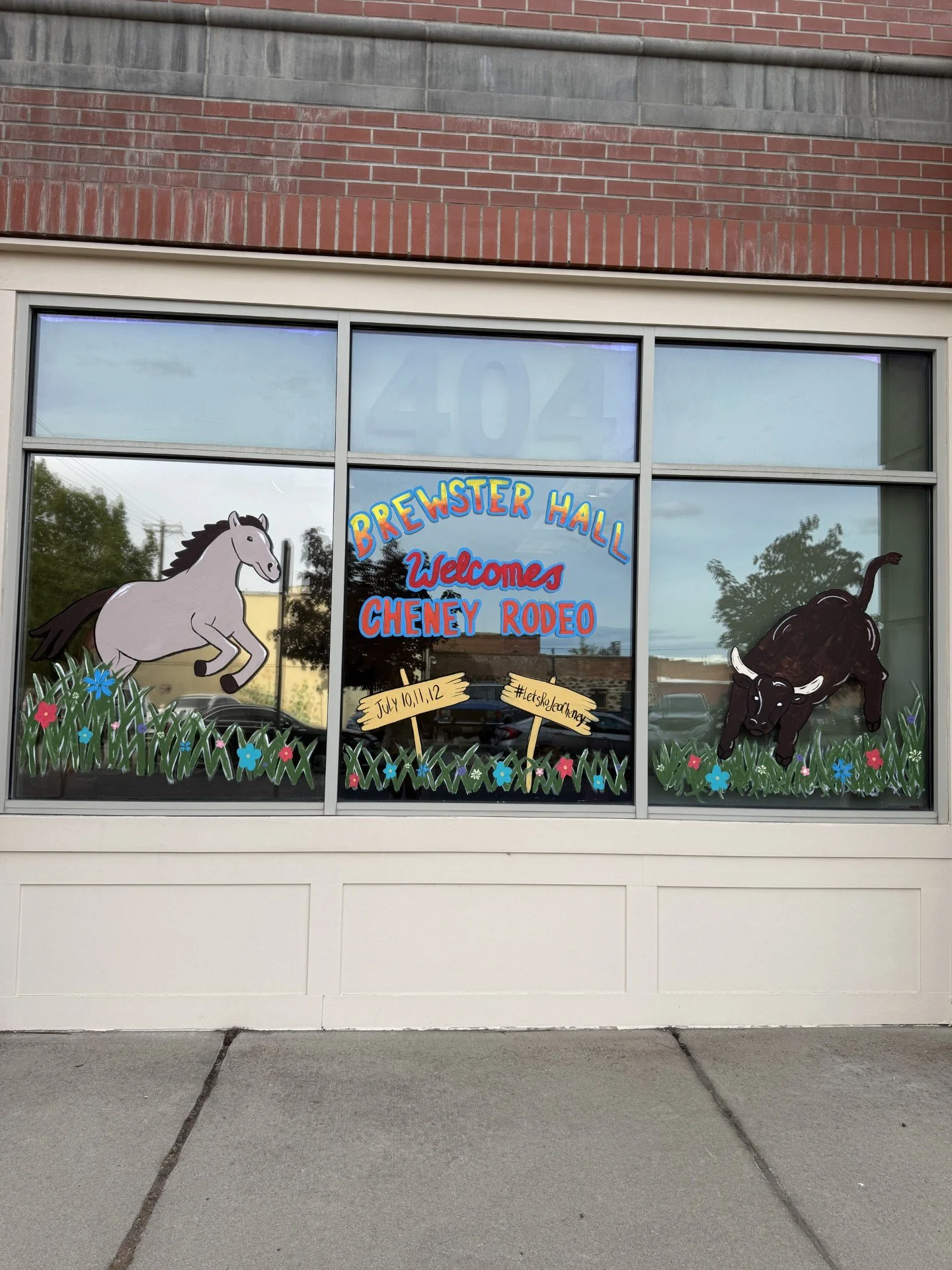 The window features signs for a tire shop, including a yellow diamond-shaped sign reading 'TIRES!' and a white sign with black text about mounting and balancing tires. There are stickers showing a checkmark inside an outline of West Virginia, logos for Alldata and other brands, and an 'Open' sign illuminated behind the glass.