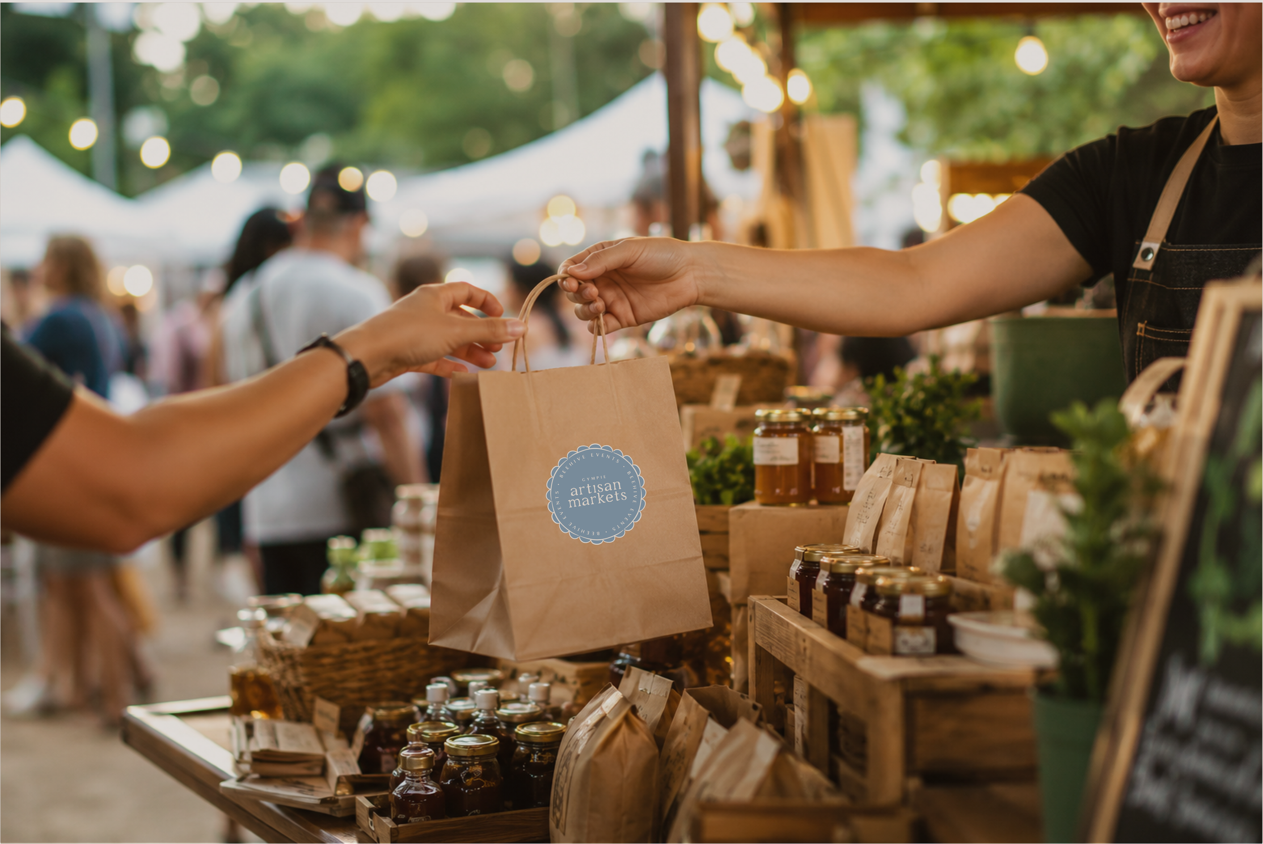 Stallholder handing over a bag at the Artisan Markets