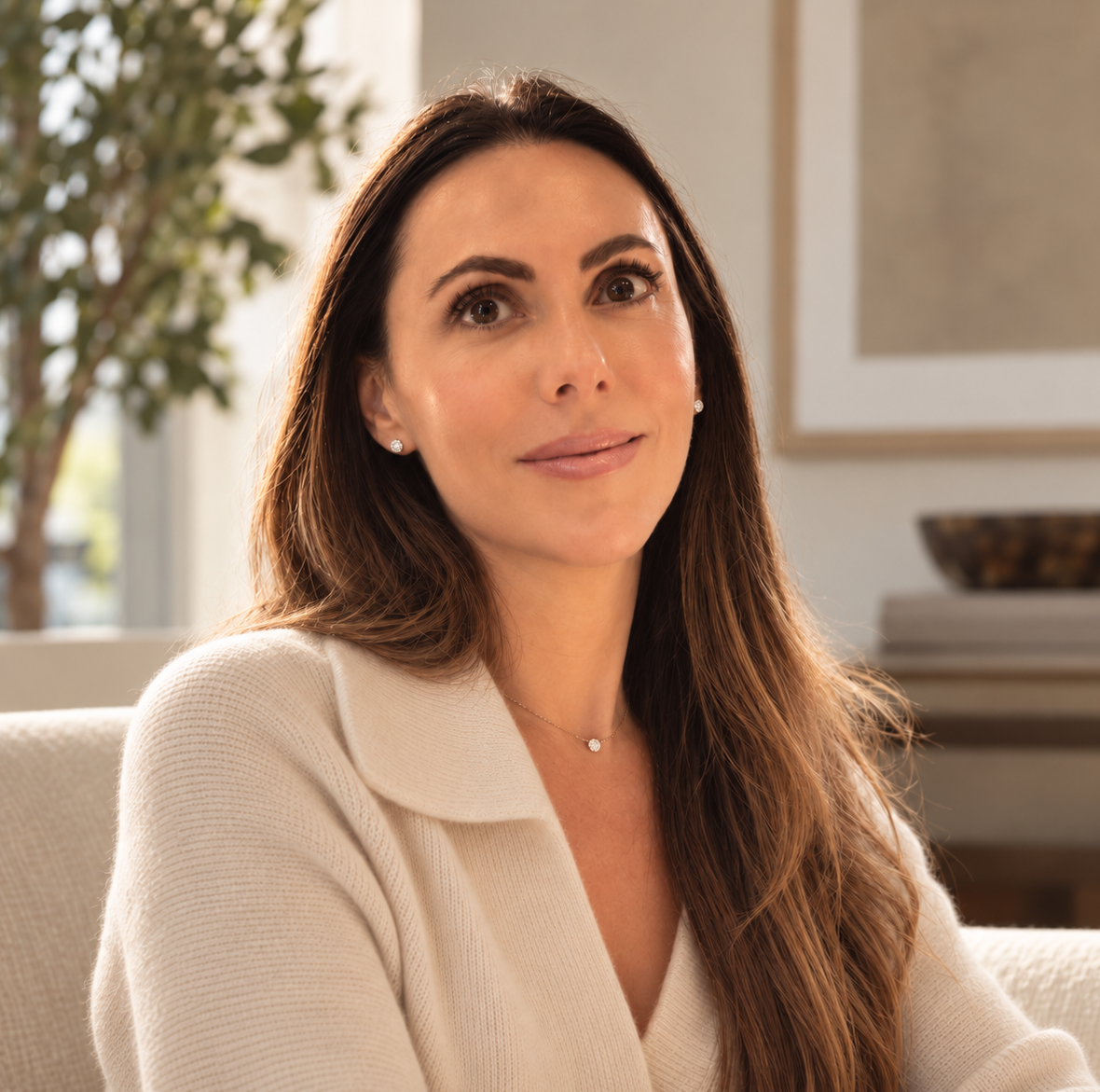 Kyra H. Newman, MFT candidate and therapist-in-training, seated indoors in a warm neutral setting.