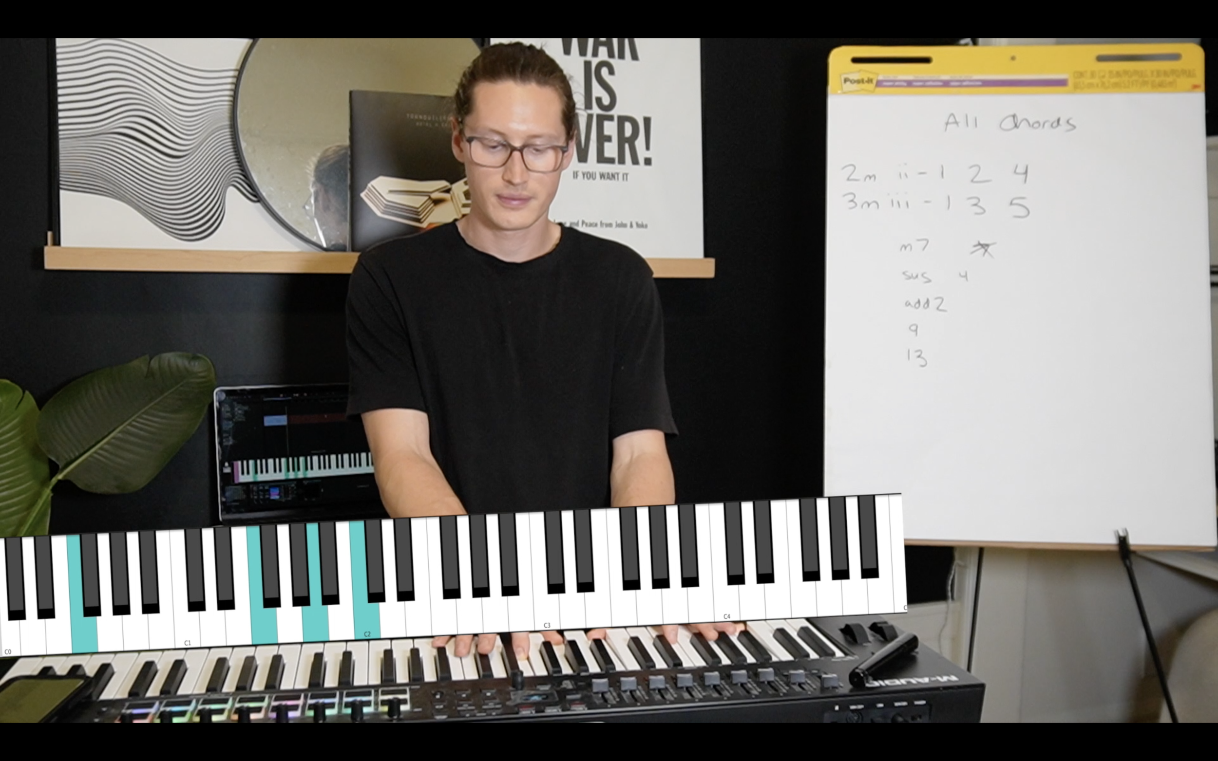 A person wearing glasses and a black t-shirt playing a keyboard with an overlay of virtual piano keys. In the background, there is a whiteboard with handwritten notes, a monitor, and a plant. The whiteboard has musical notes and chords written on it.