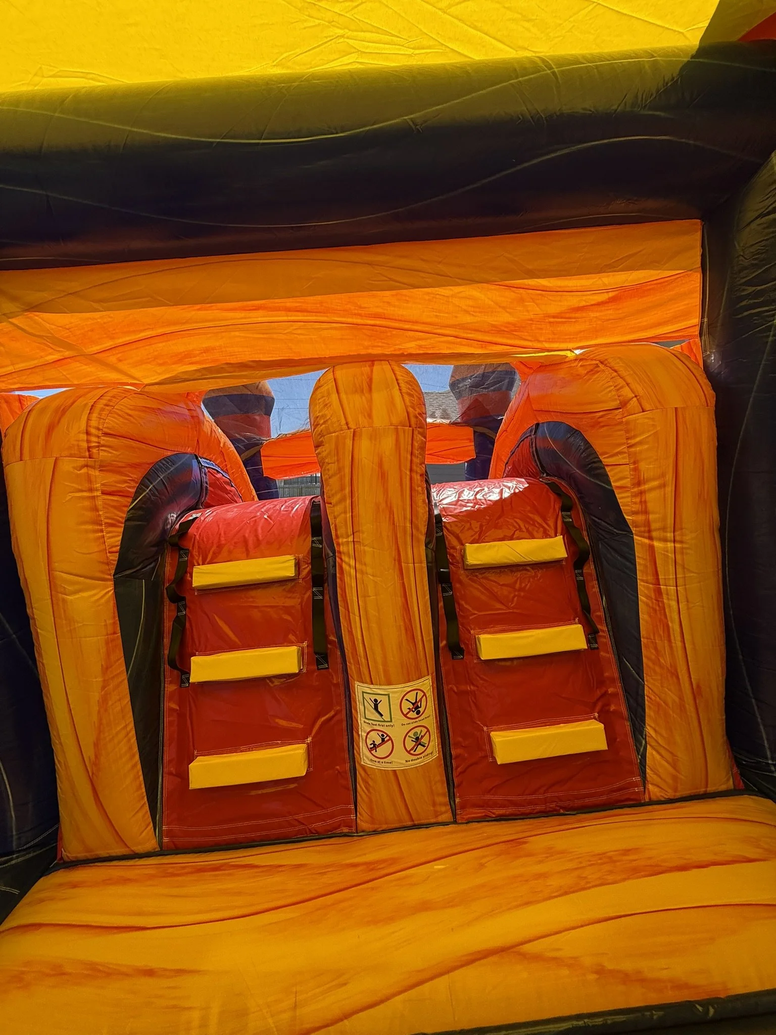 Inside of a bright orange emergency escape slide with safety instructions sticker visible.