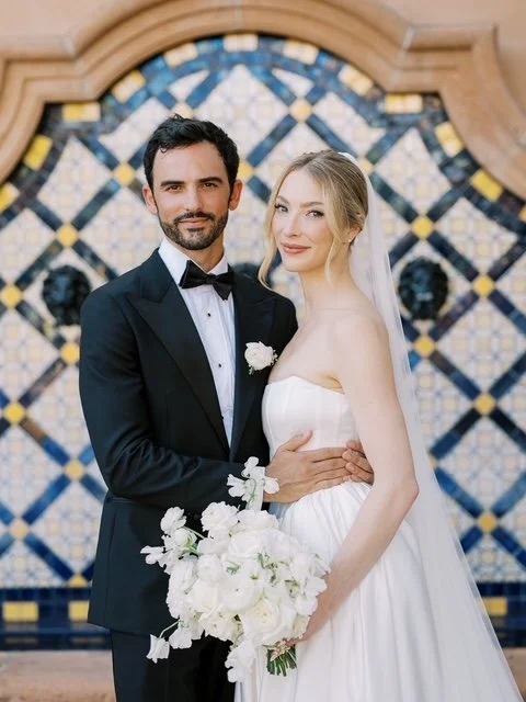 Bride with soft classic glam bridal makeup and groom in a black tuxedo posing in
front of a blue and yellow Spanish tile fountain at Rancho Valencia in Rancho Santa Fe, CA