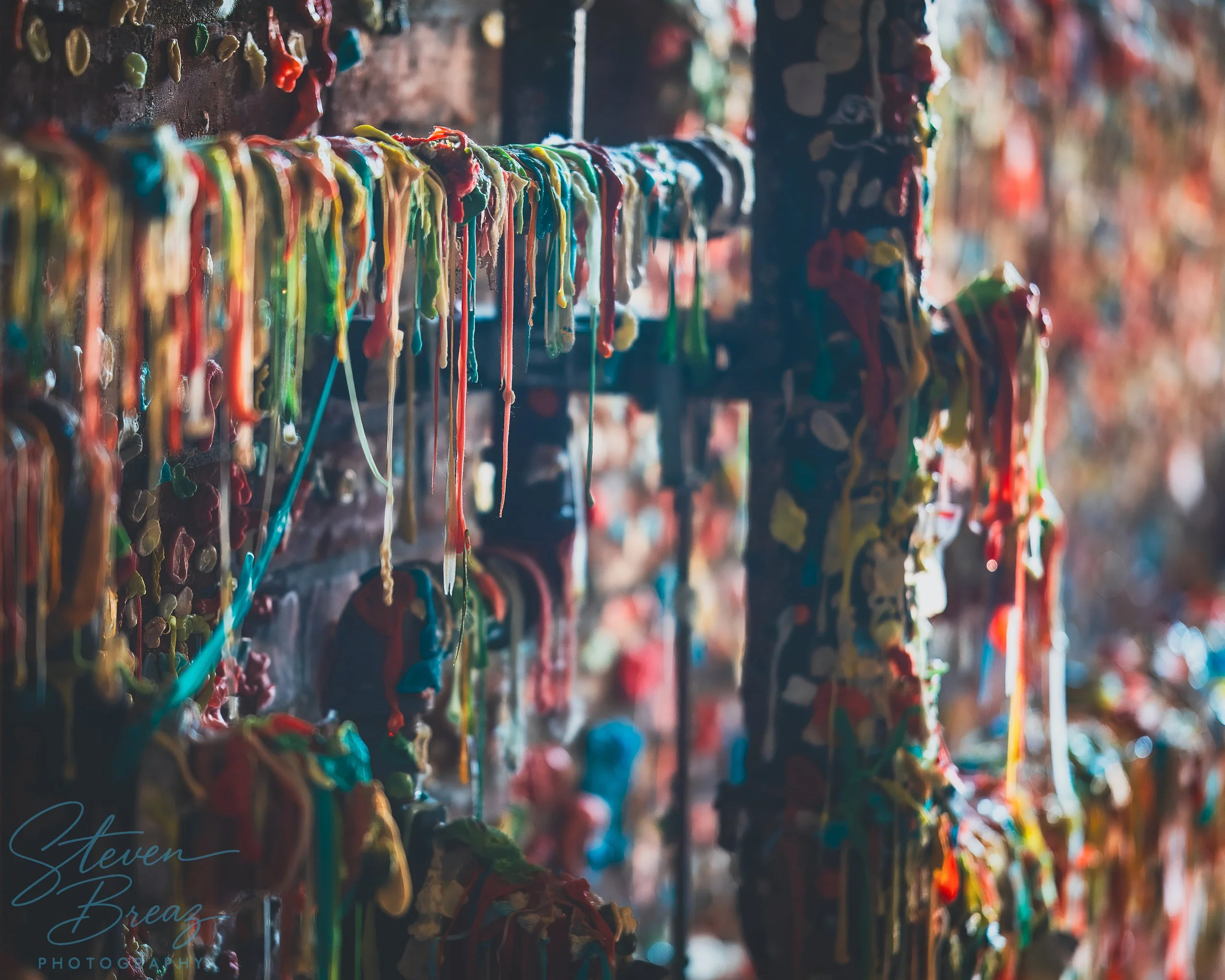 Colorful strings of chewing gum stretched and stuck onto a wall  at Pike Place market.