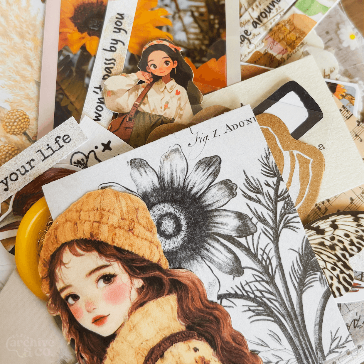 close-up of themed junk journal ephemera with illustrated character, botanical details, layered papers, photographs, stickers, and decorative pieces