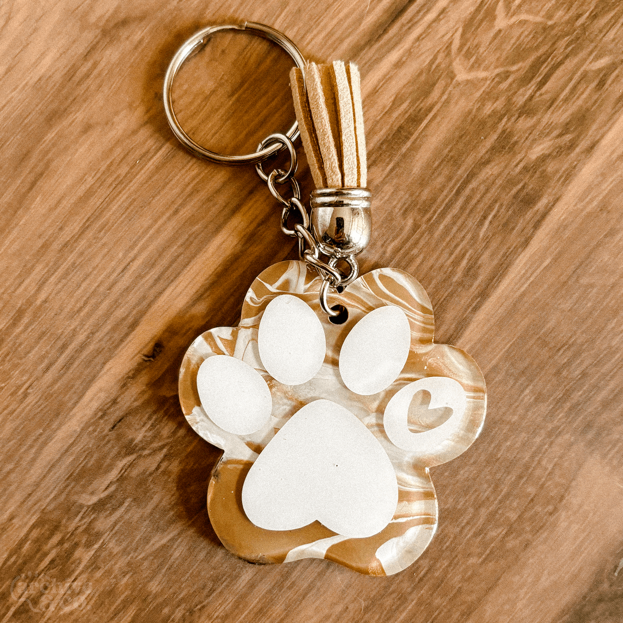 handmade paw print keychain with brown and white marbled fur-inspired pattern, white paw details, tassel, and silver keyring