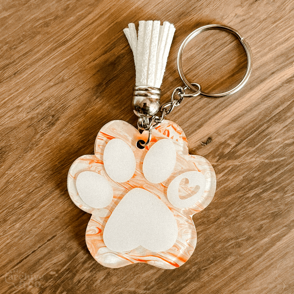 handmade paw print keychain with ginger and white marbled fur-inspired pattern, white paw details, tassel, and silver keyring