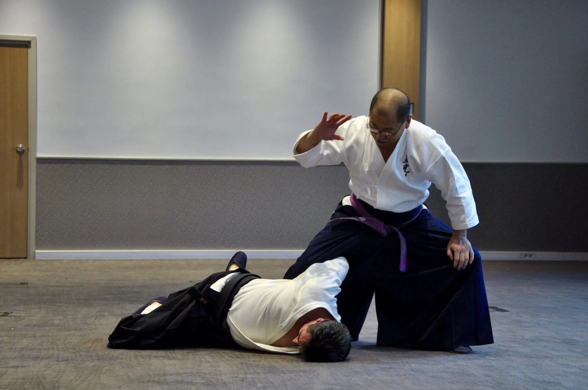 Soke Irie of KoKoDo JuJutsu demonstrates a technique on a student lying on the floor, inside a budokan in Japan