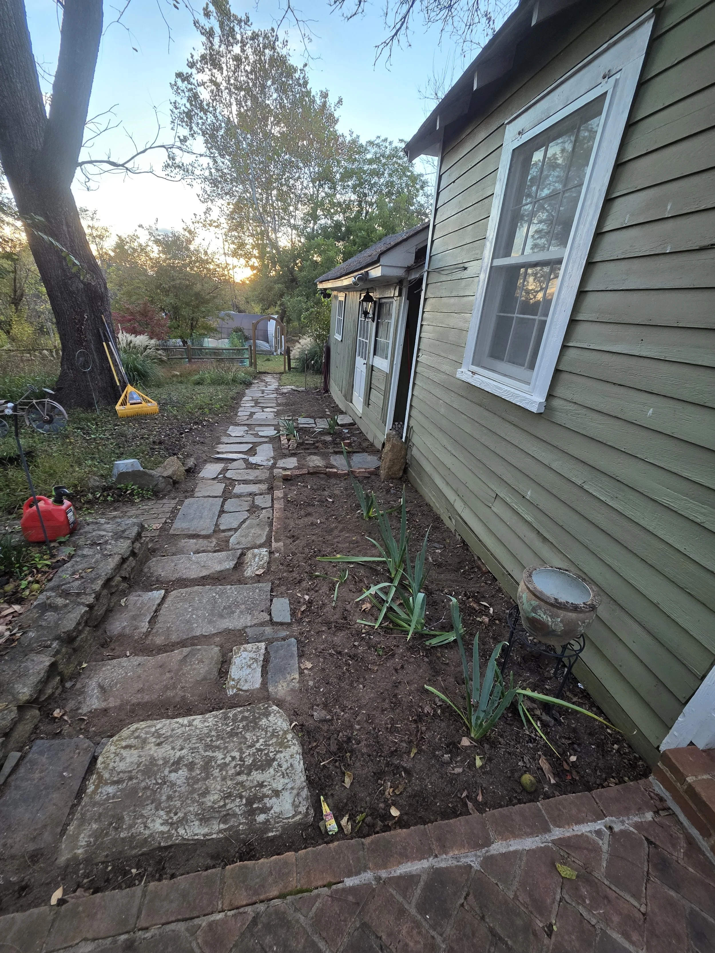 A section of the reclaimed historic flagstone walkway at Edgewood, running alongside a green-paneled building.