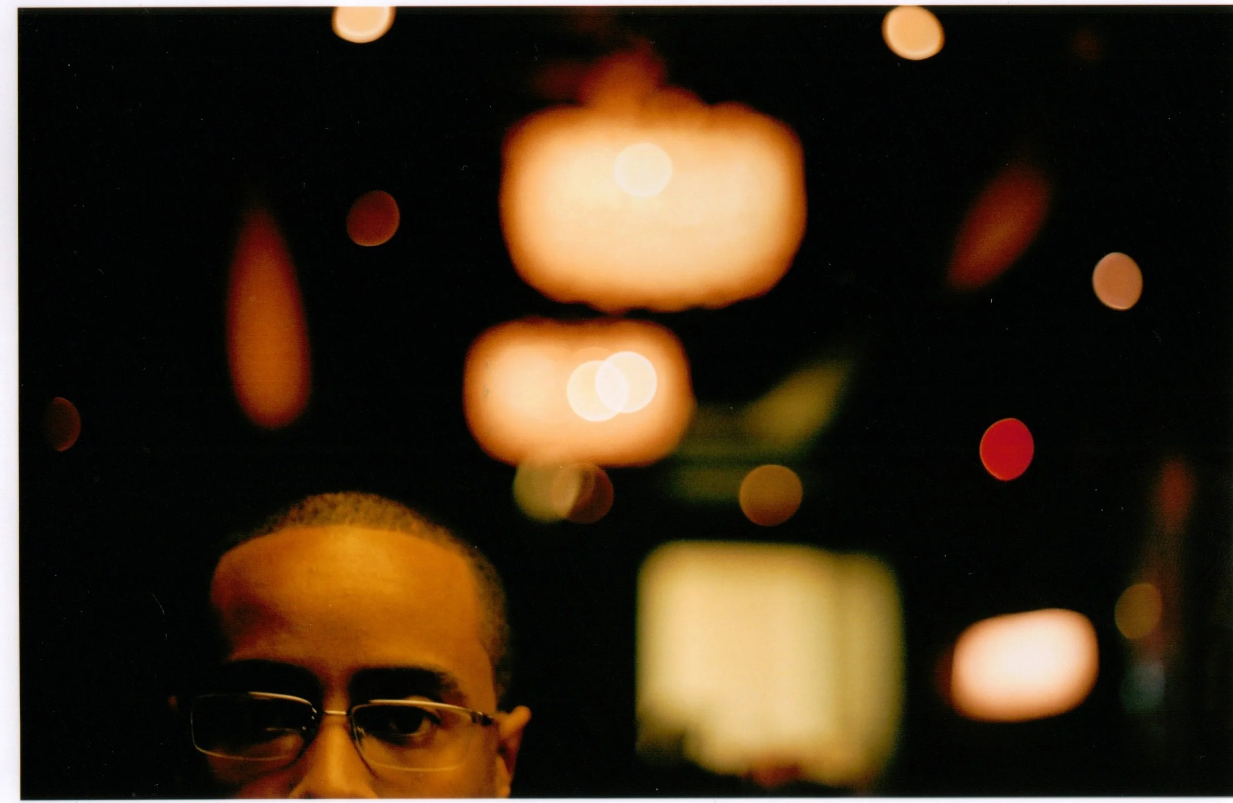Person wearing glasses at night with colorful blurred lights in the background.
