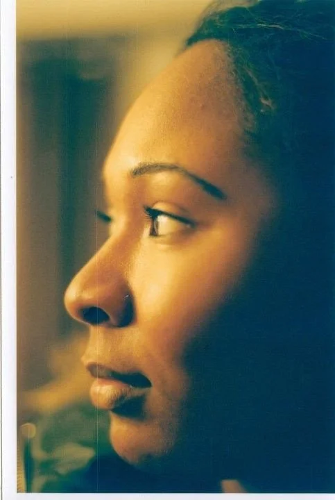 Close-up of a young African American woman in profile, looking to her left with a neutral expression.