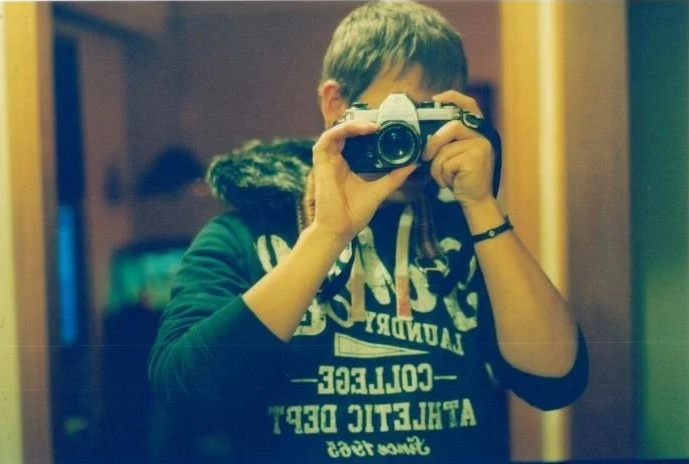 Joel taking a photo with a camera in front of a mirror.