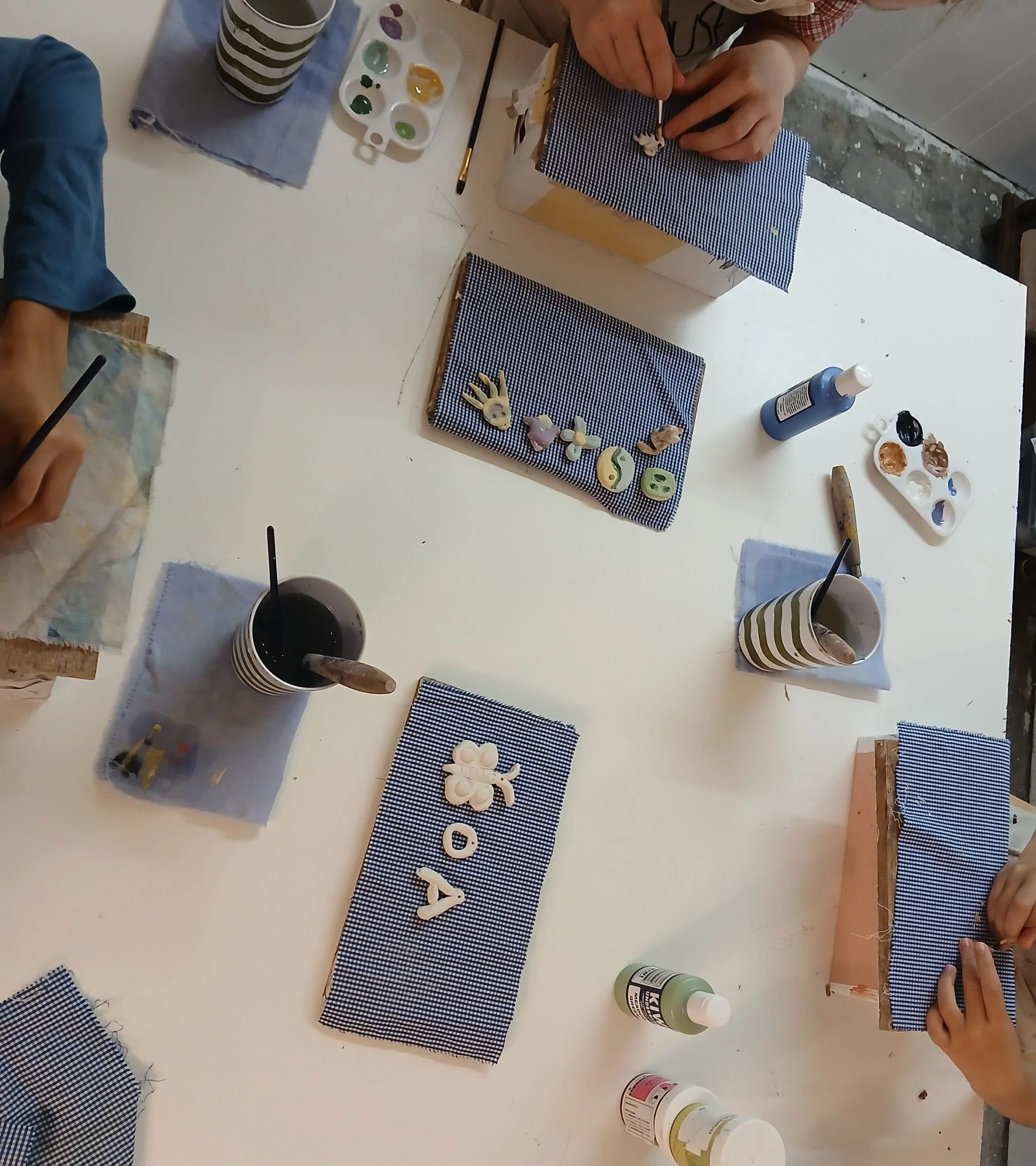 Kids underglazing their clay creations at the studio