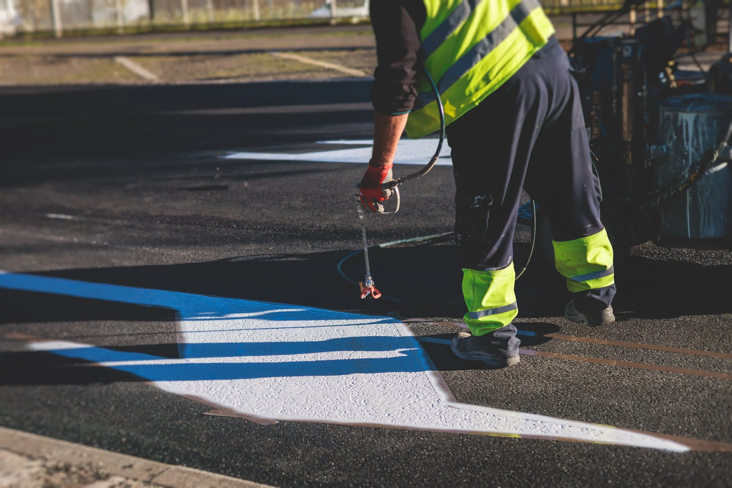 A man painting white pavement markings on the road