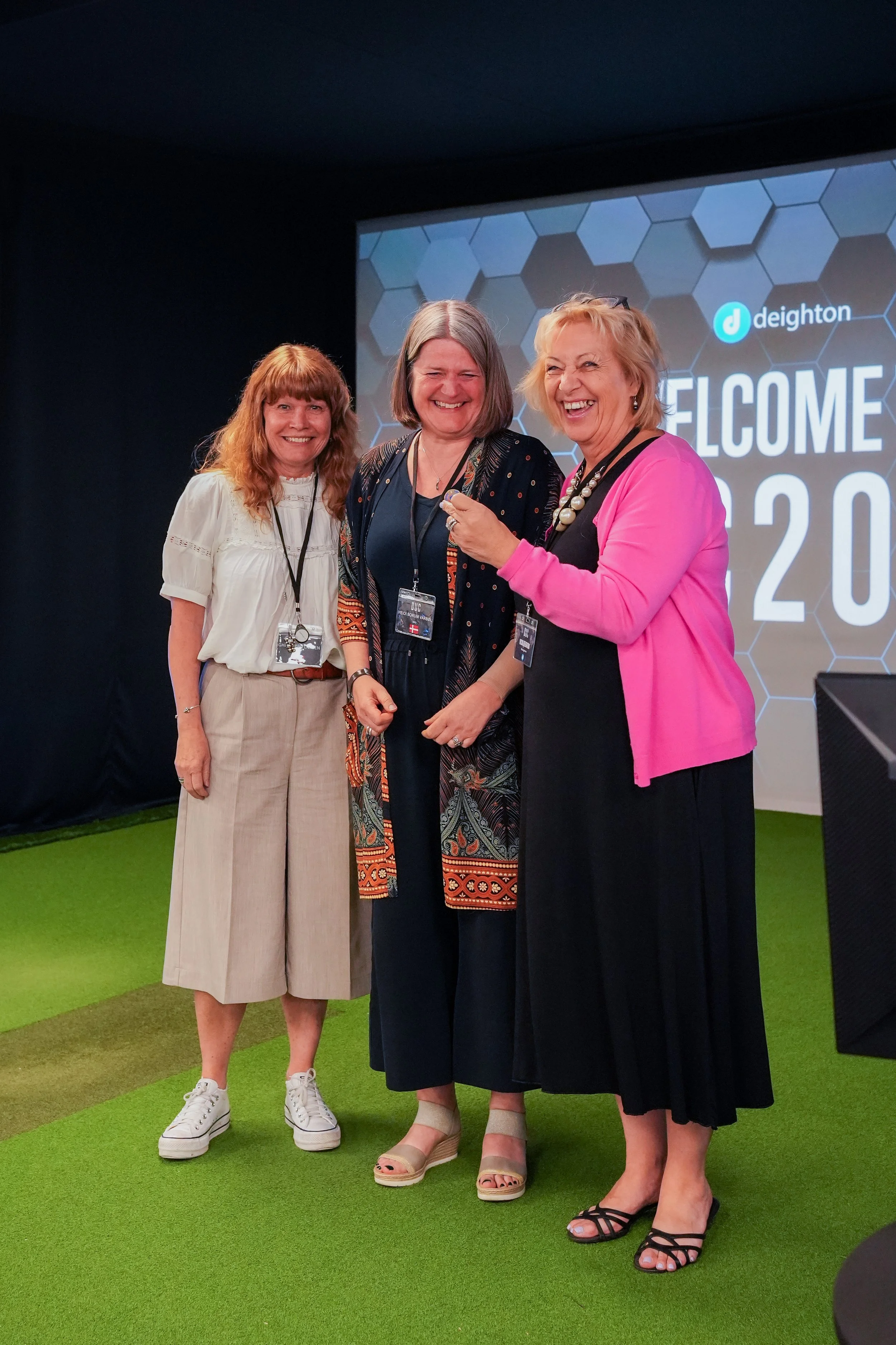 Two members of Deighton's client DRD pose with Vicki Deighton who is holding their 5 year anniversary pin.