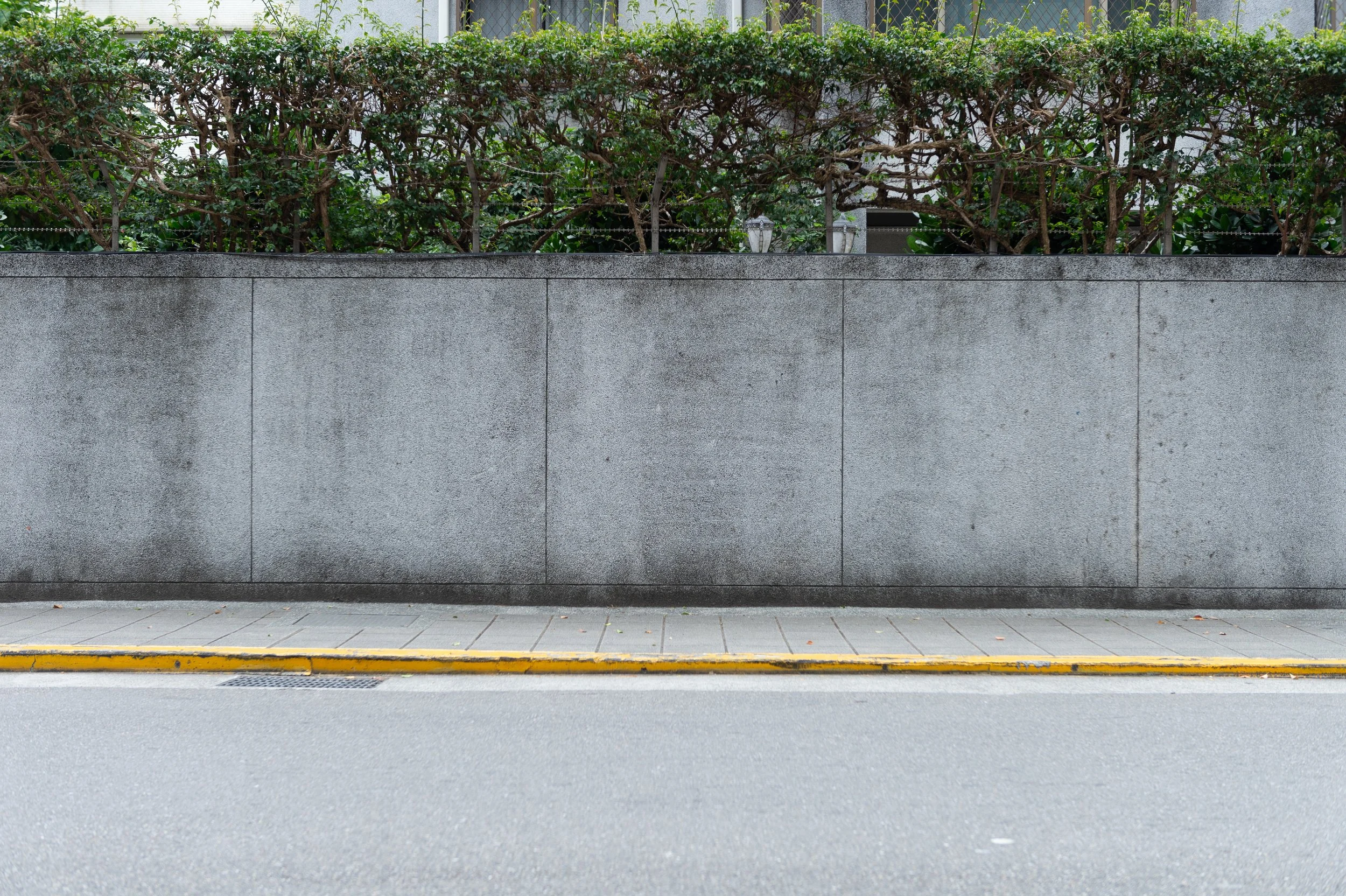 A sidewalk with yellow painted curb and retaining wall