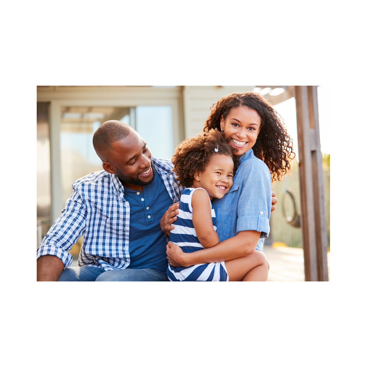 A happy family of three, including a man, woman, and young girl, enjoying an outdoor moment and smiling at the camera.