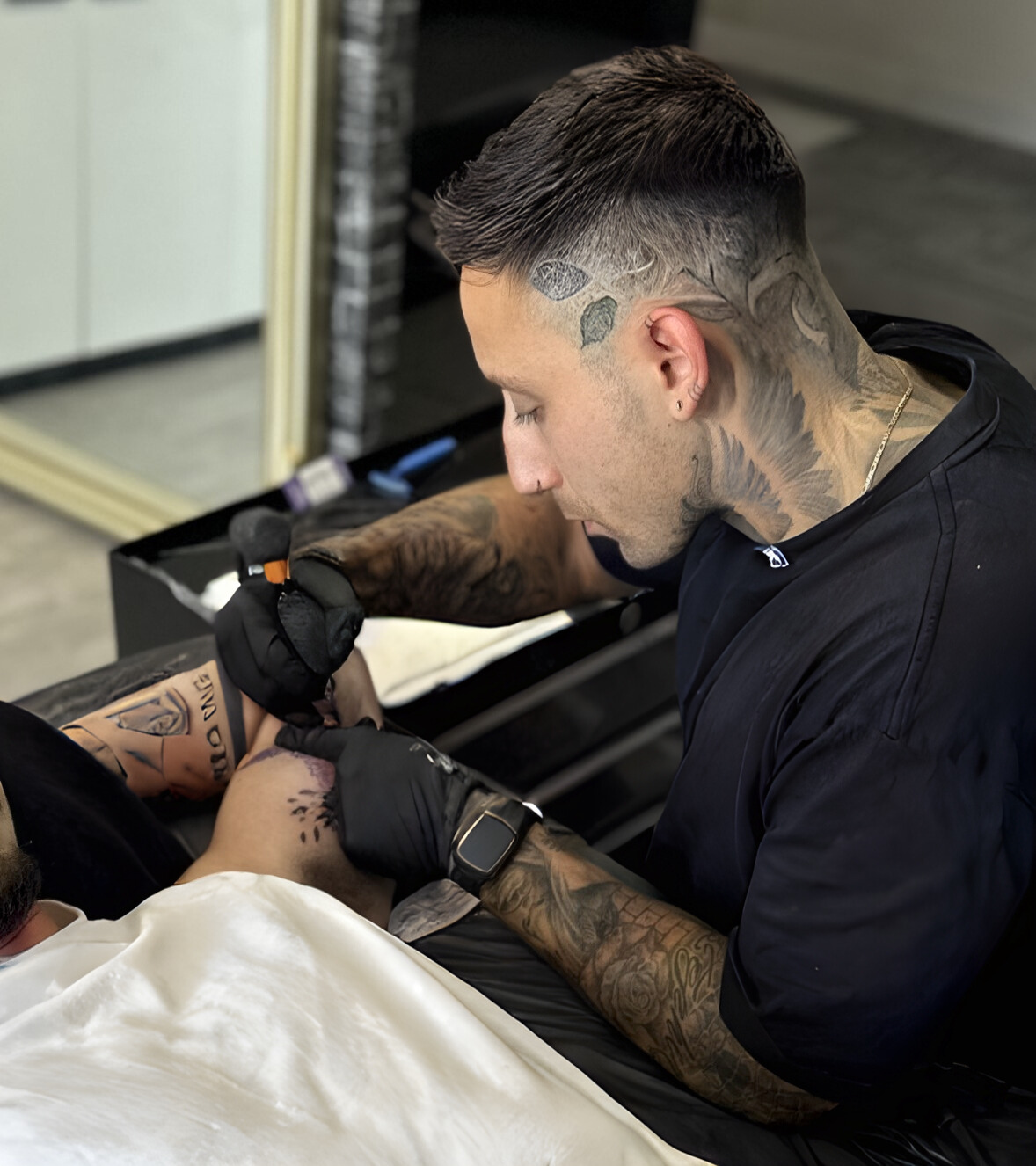 Tattoo artist working on a client's arm.