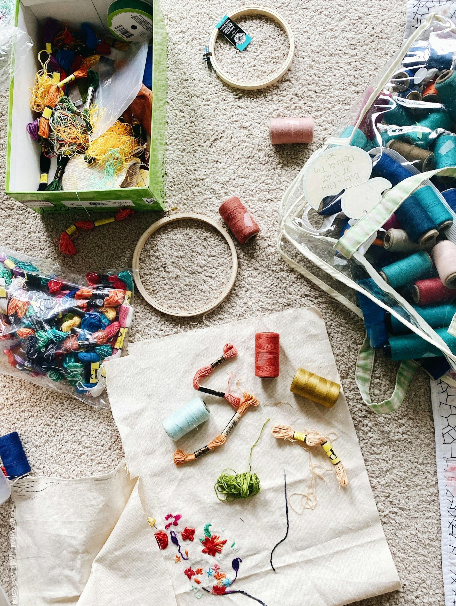 beige carpet with bozes of embroidery threads and unfinsihed embroidery