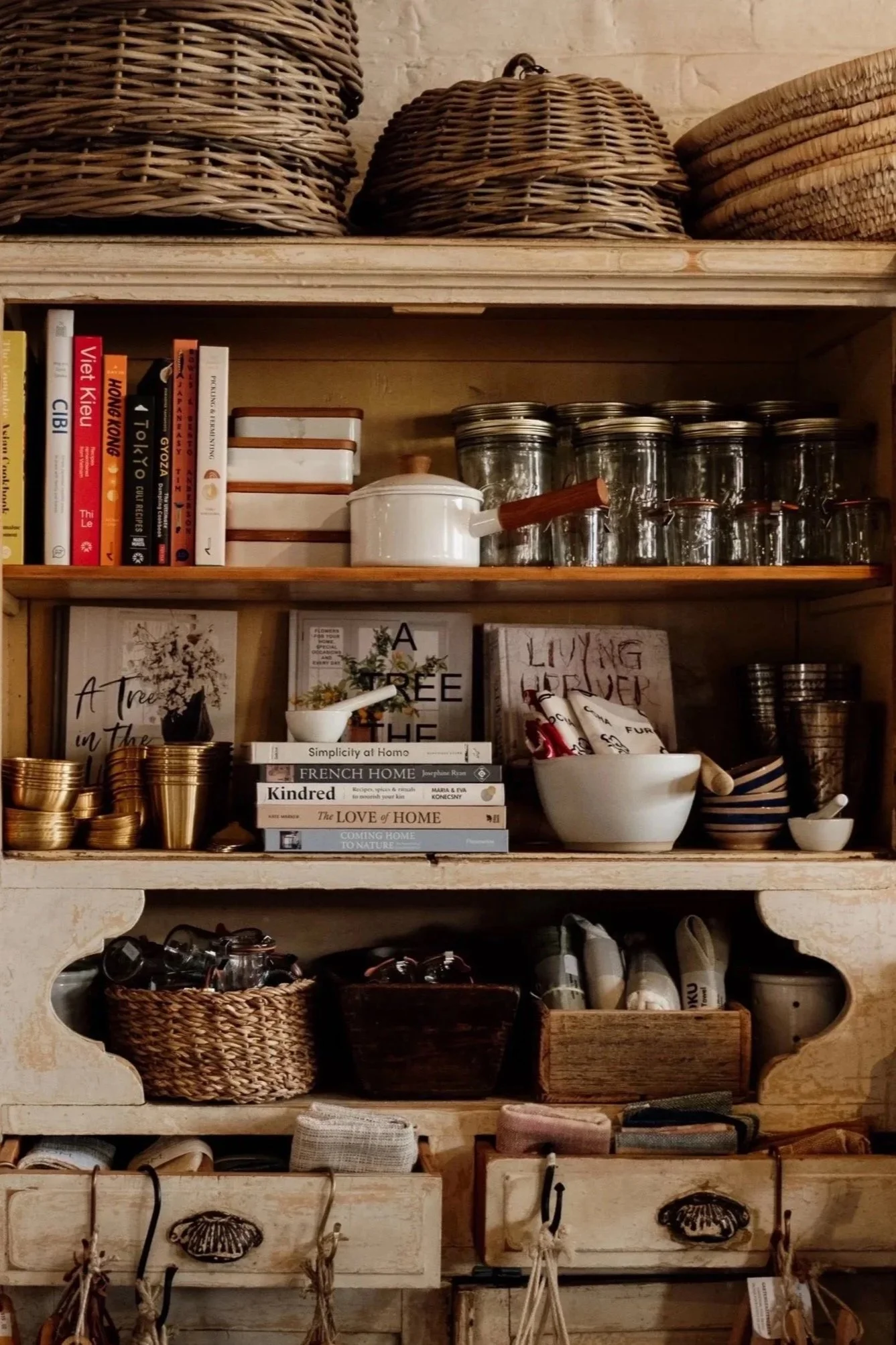 Wooden shelf styled with kitchenware, books, baskets and pantry jars