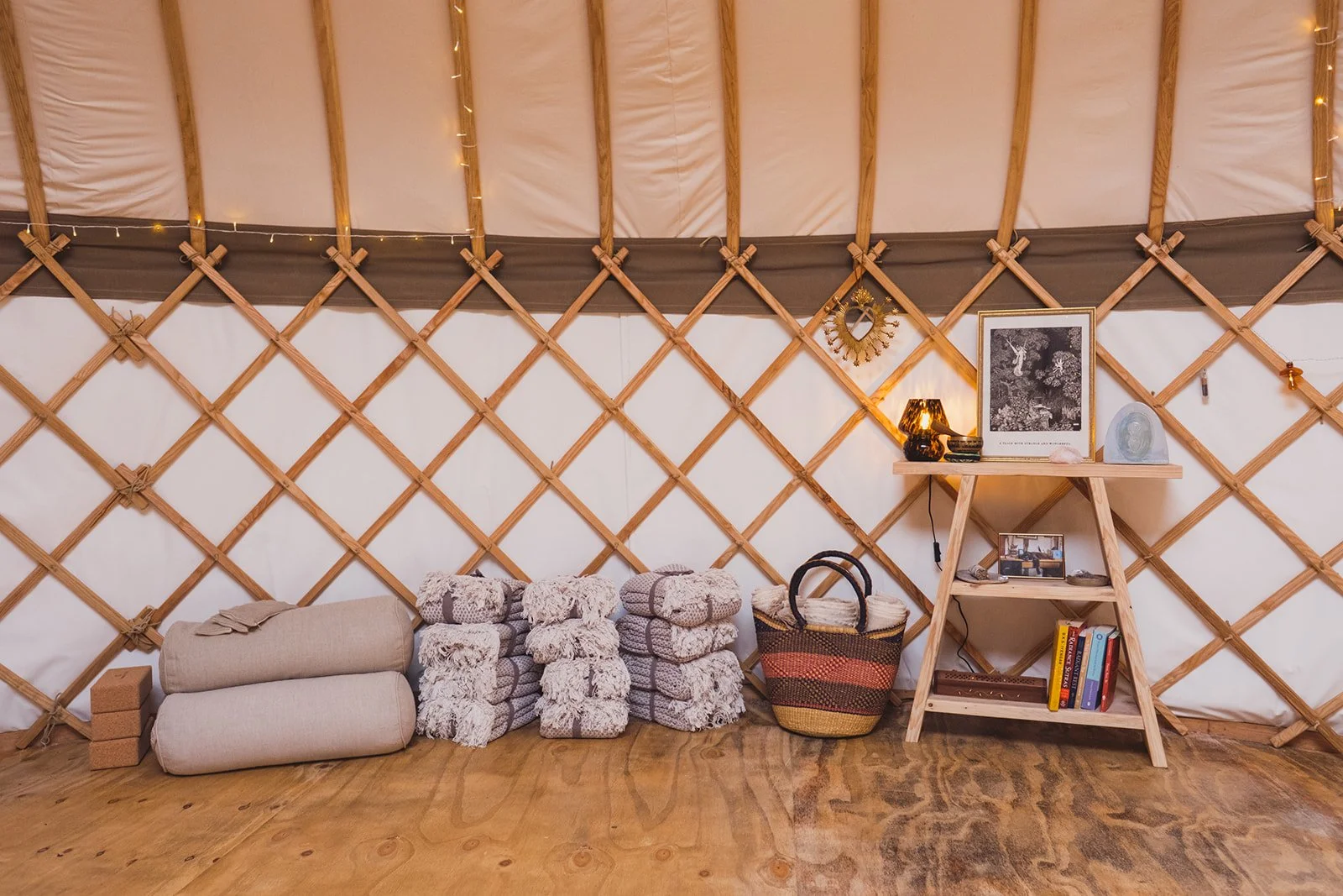 A view of some of the blankets, bolsters, yoa blocks, and a shelf inside the yurt.