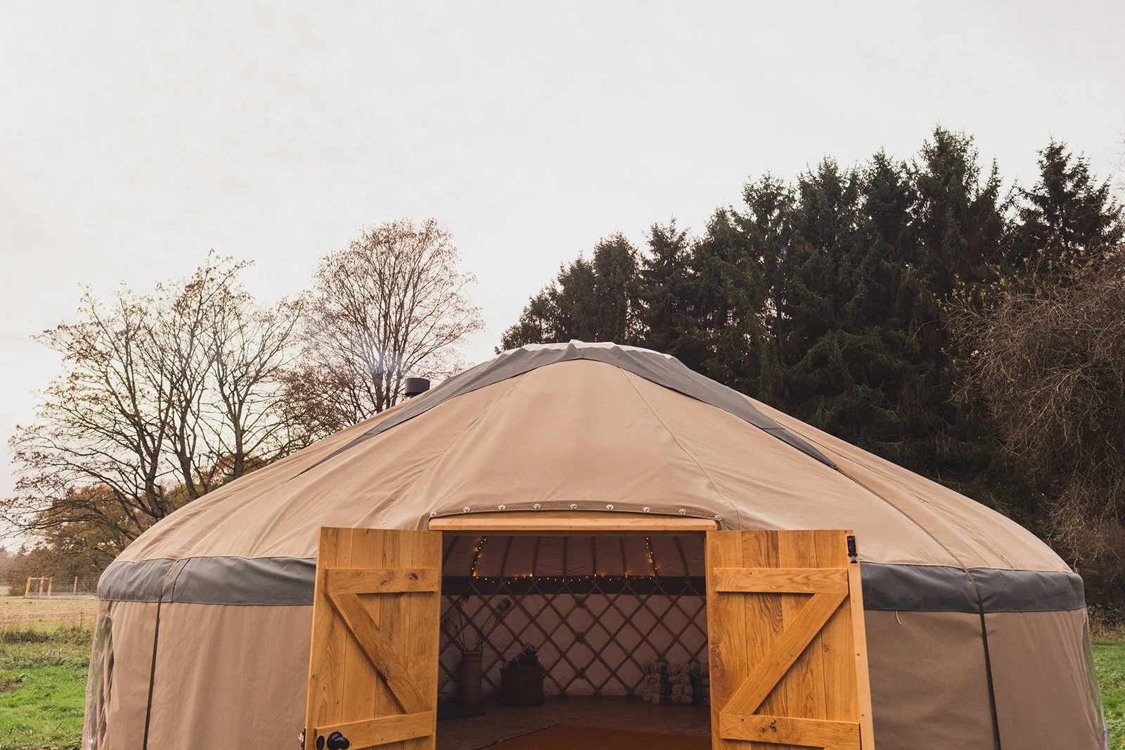 An inviting image of the exterior of The Whiteleaf Yurt with the doors open to show the interior.