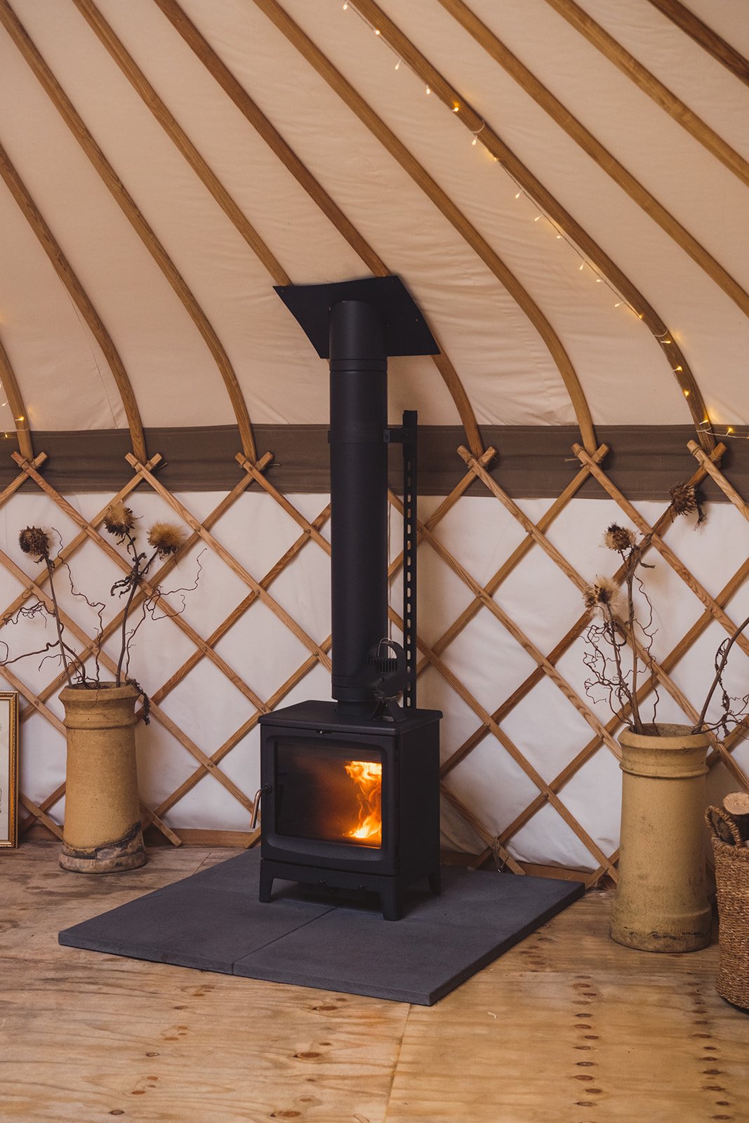 Interior view of The Whiteleaf Yurt, with an inviting fire in the woodburner.