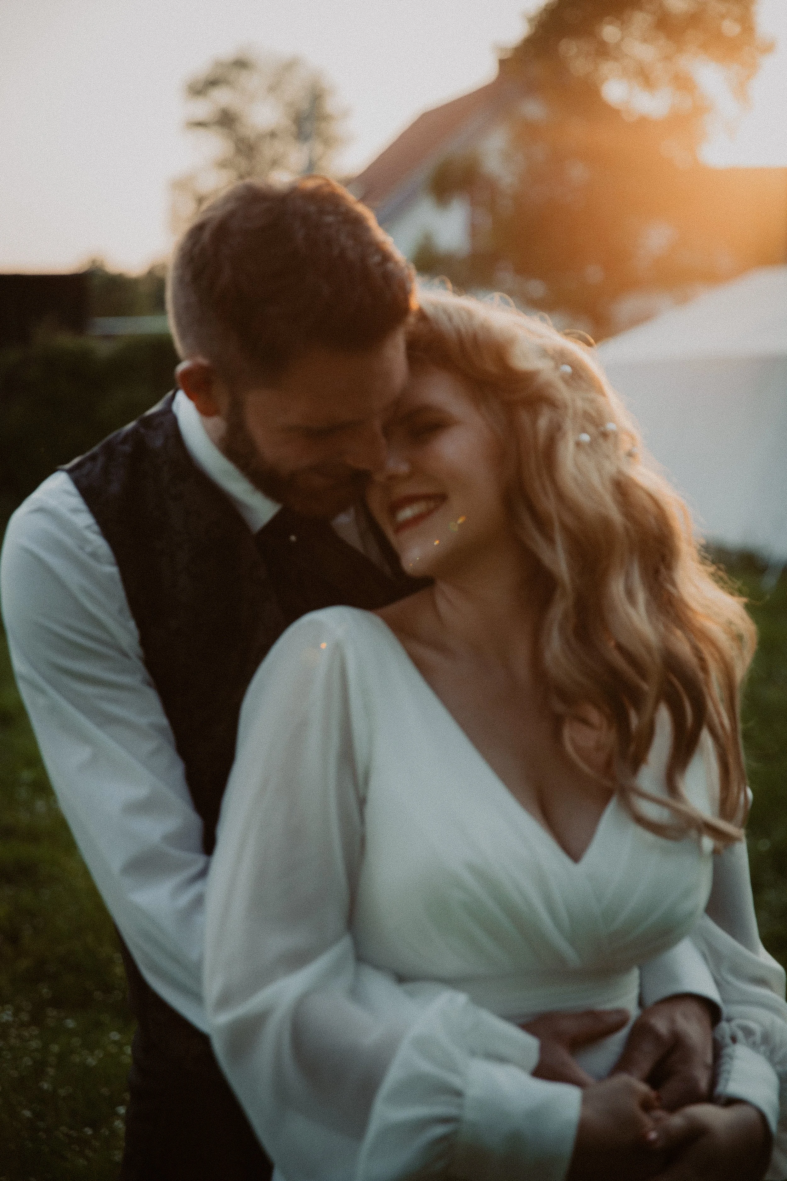 Ein Paar bei einem Glücksmoment im Freien bei Sonnenuntergang, umarmend und lachend.