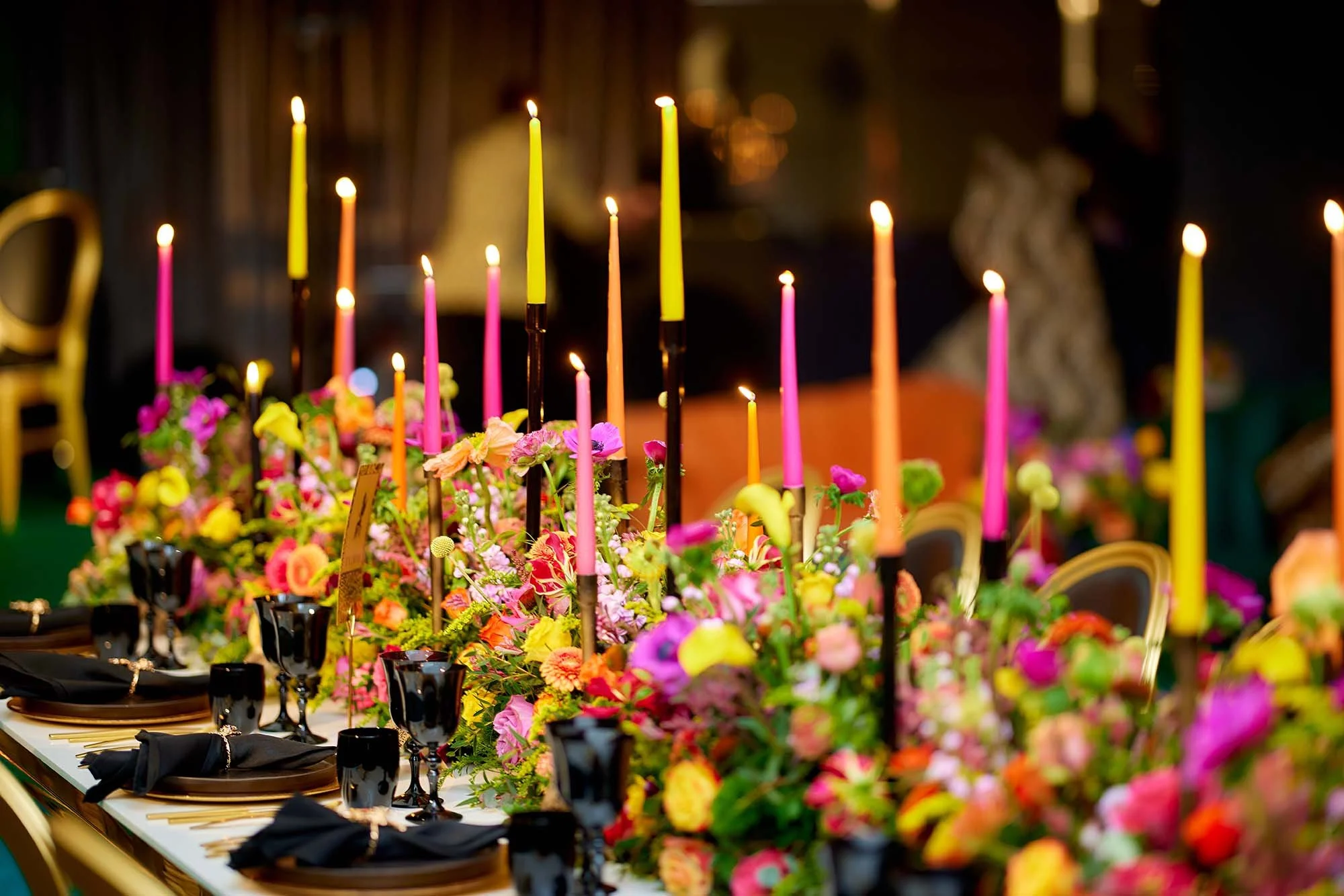 Event table setting consisting of pink, yellow and orange flowers and candles.