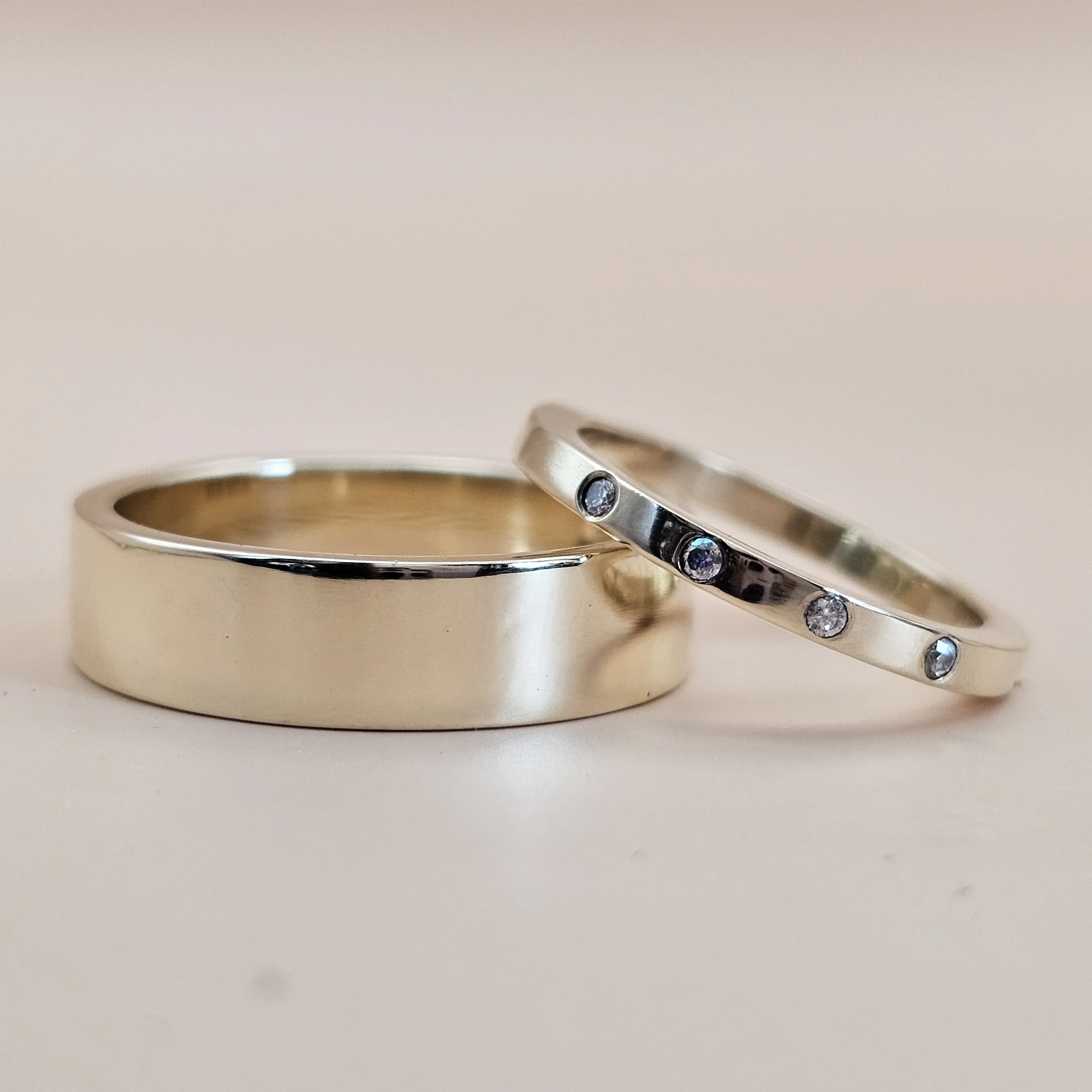 Close-up of a shiny silver wedding band with embedded gemstones resting on a white surface.