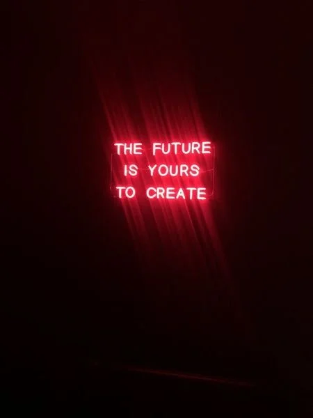 Red neon sign reading 'The future is yours to create' against a dark background.