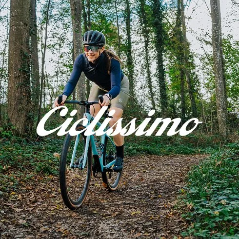 Mulher andando de bicicleta em trilha na floresta com a palavra 'Ciclisso' em destaque