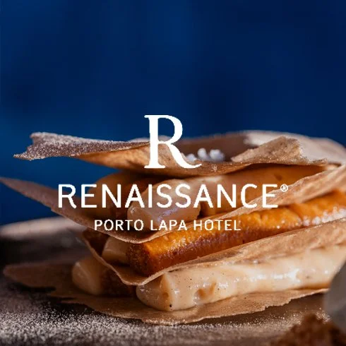 Detalhe de um prato com camadas de massa, recheio e cobertura, com o logo do hotel Porto Lapa na frente