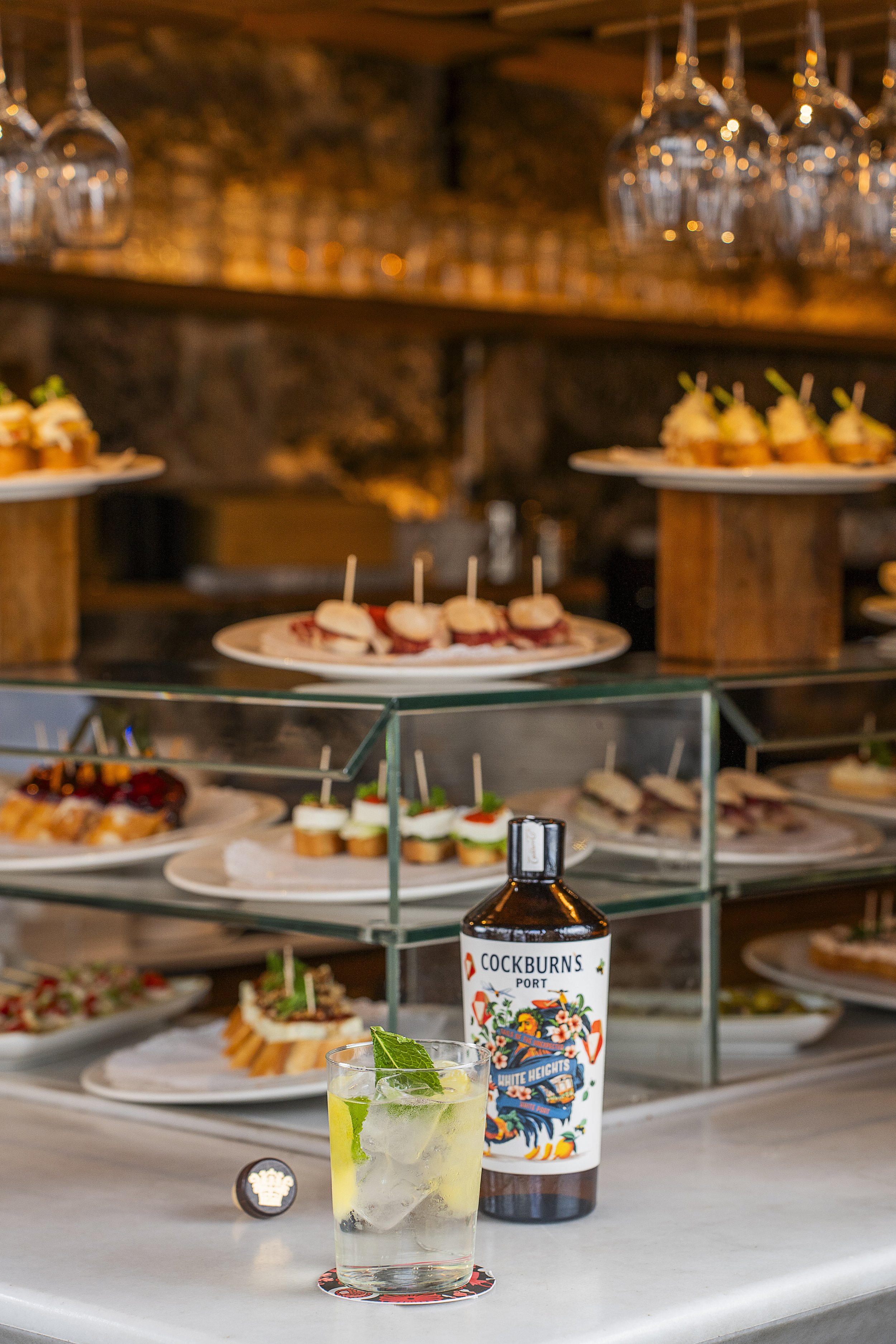 aperitivos e drinks em uma mesa de um bar ou restaurante, com garrafas de vodka e copo com gelo, hortelã, cítricos, que parecem mojitos.