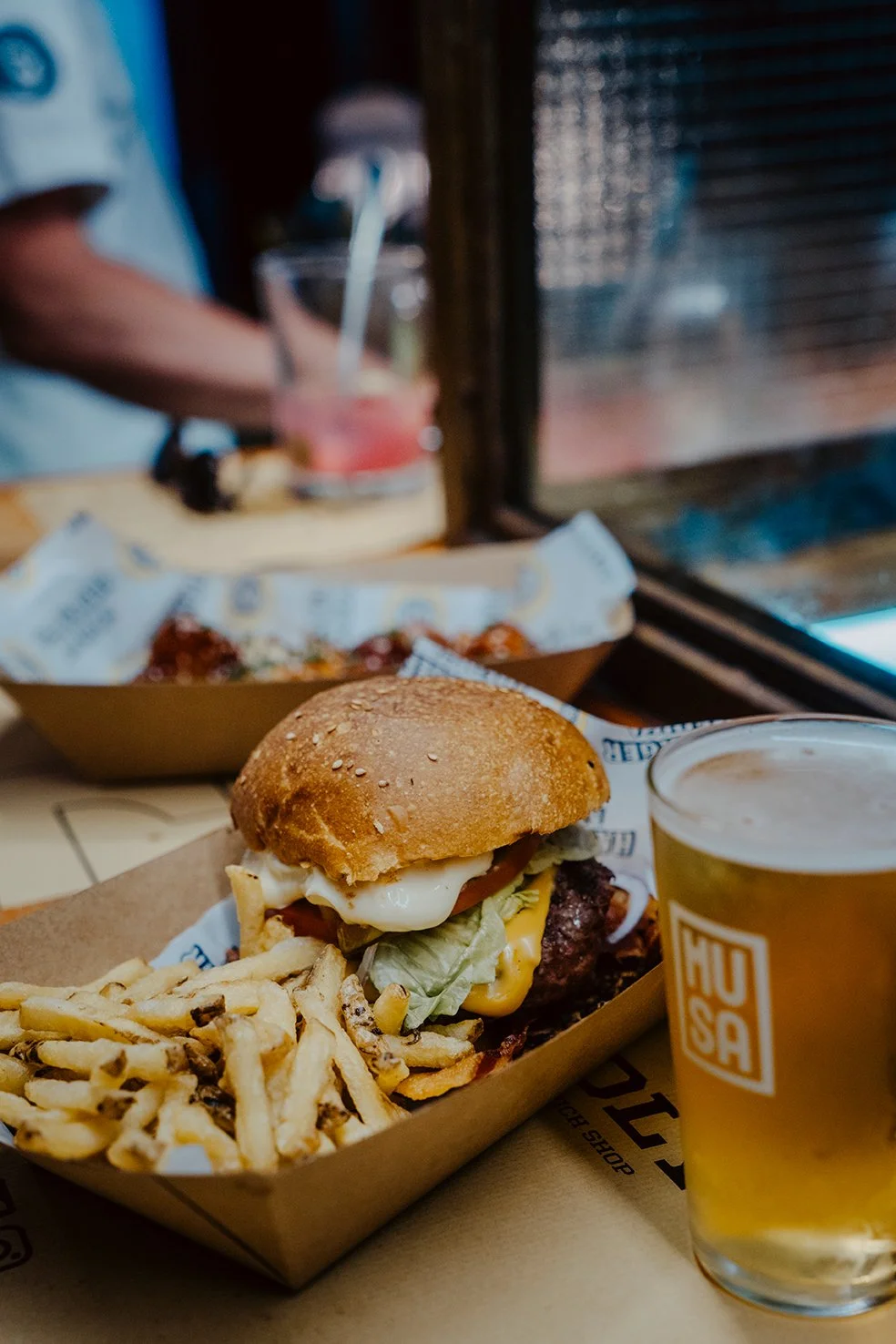 Sanduíche de hambúrguer com batatas fritas e uma cerveja artesanal em um restaurante