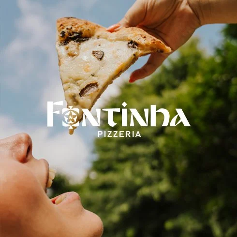 Mão segurando uma fatia de pizza com queijo e ingredientes diversos, sendo apresentada a uma criança ao ar livre, com o logotipo da pizzaria Fontinha no centro da imagem.